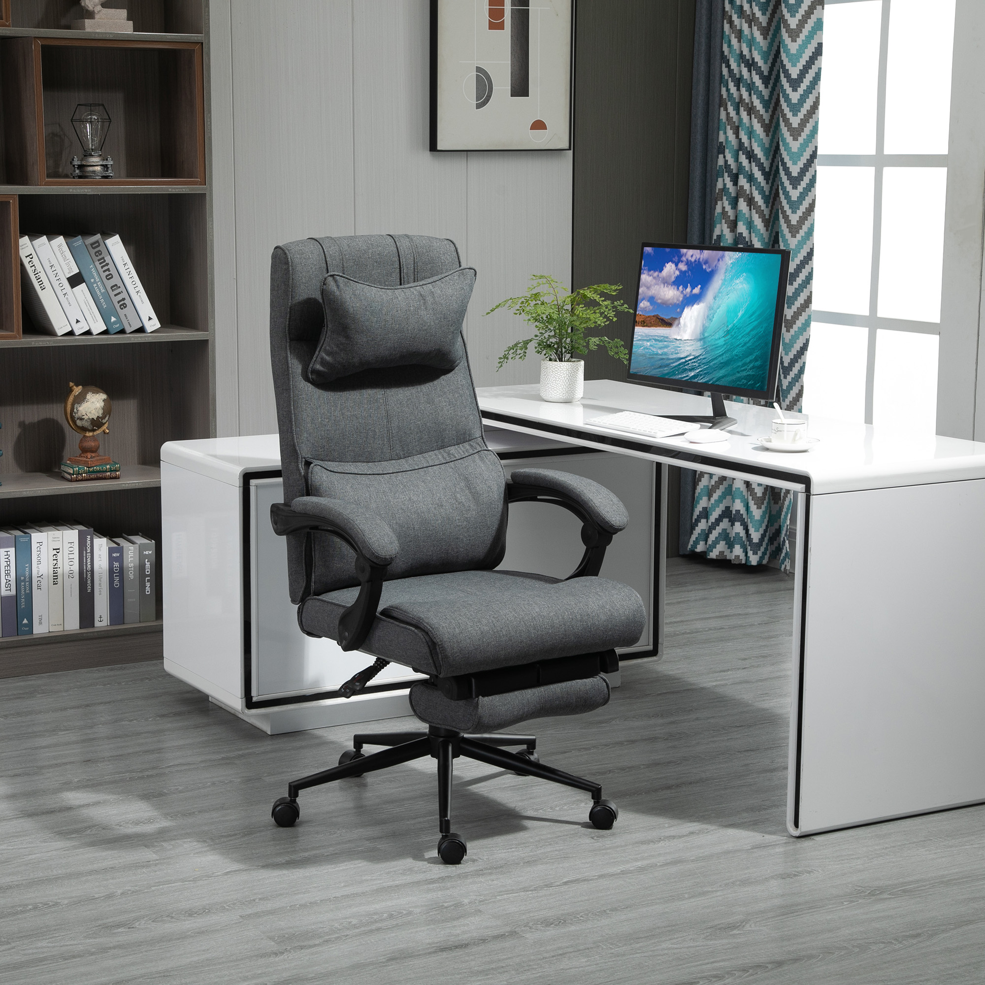 Sedia da ufficio con cuscino e poggiatesta grigi. Scrivania bianca con monitor.