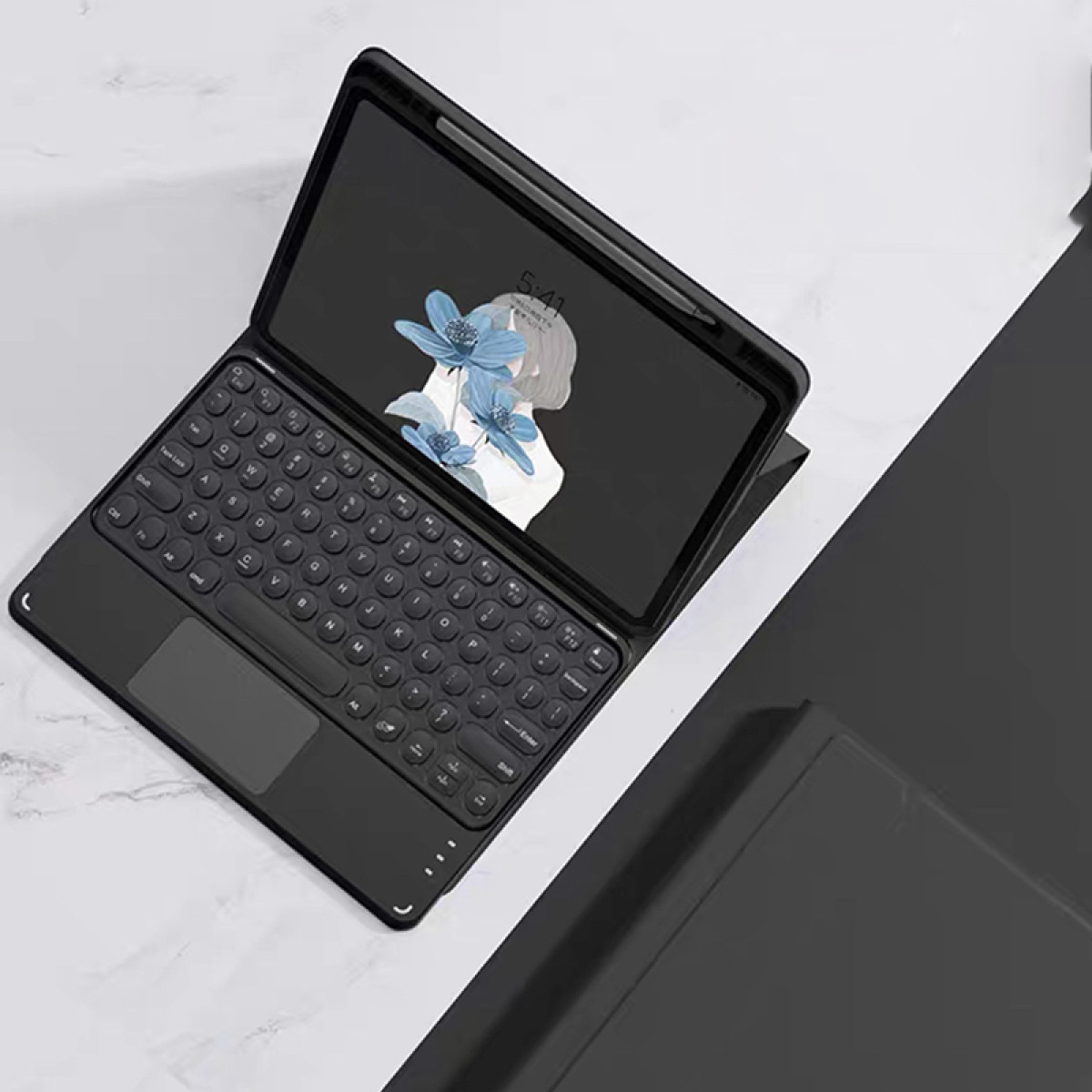 Schwarzes Tablet mit angeschlossener Tastatur und Stift. Der Bildschirm zeigt ein Bild einer Person und Blumen.