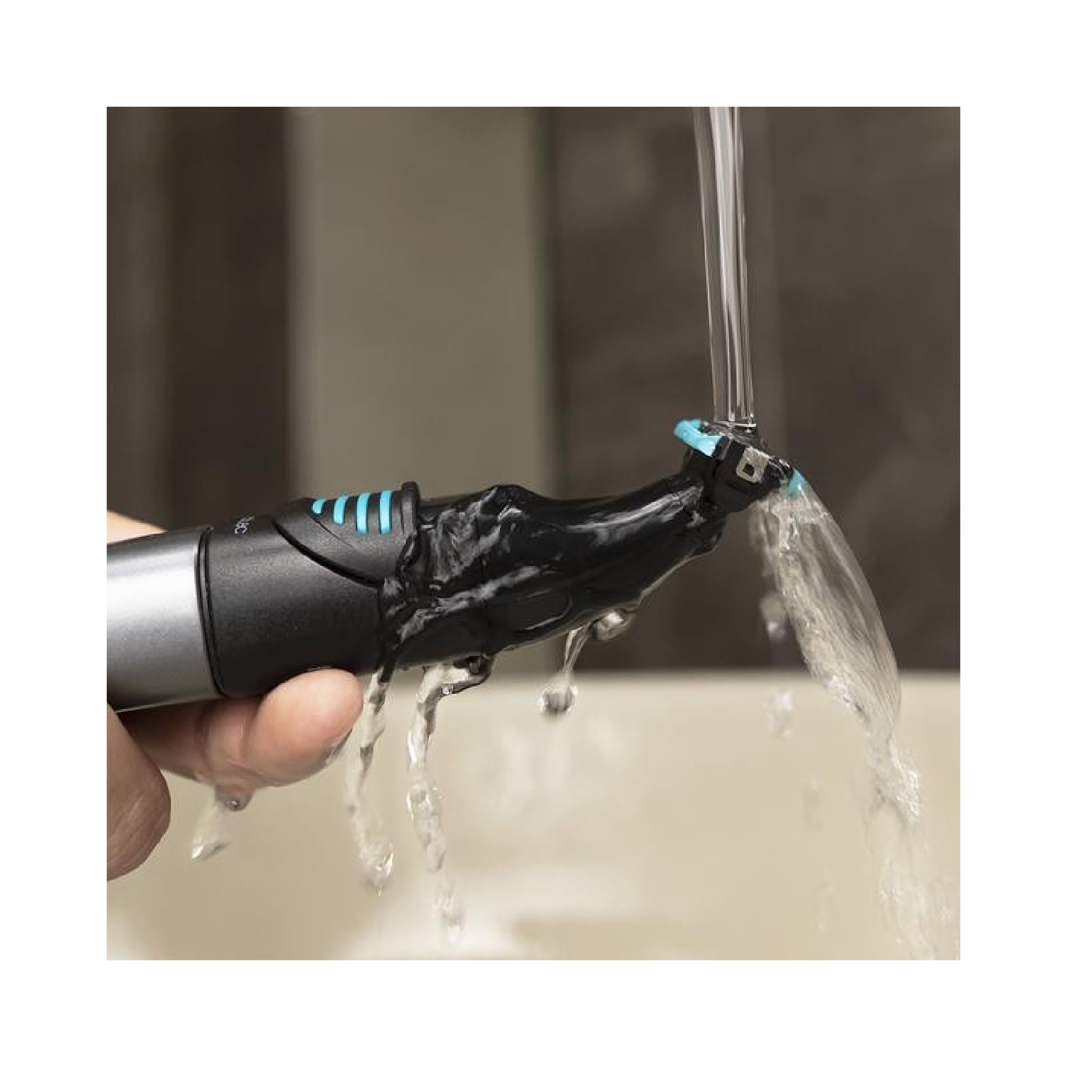 Un rasoio elettrico nero sotto l'acqua corrente, tenuto da una mano.