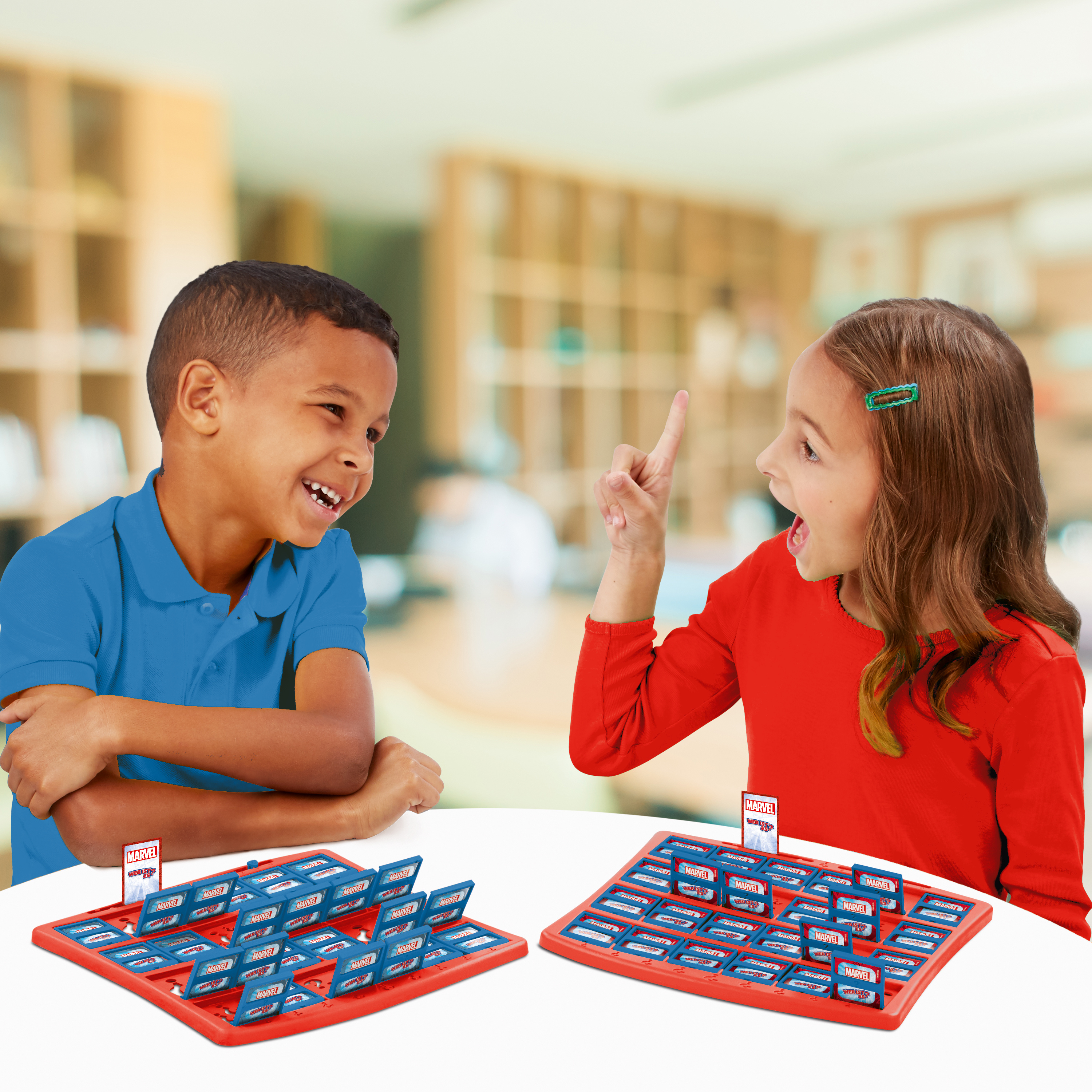 Zwei Kinder spielen ein Brettspiel. Eines zeigt nach oben und lächelt. Brett rot.