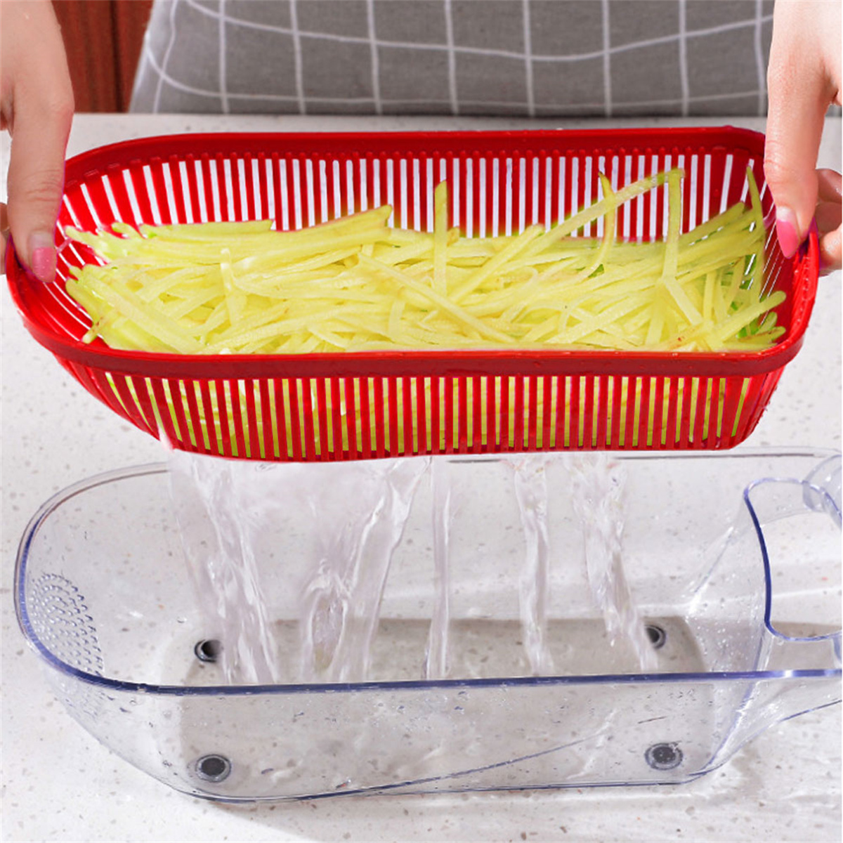 Roter Seiher mit gelben Kartoffelstreifen über einem Waschbecken.