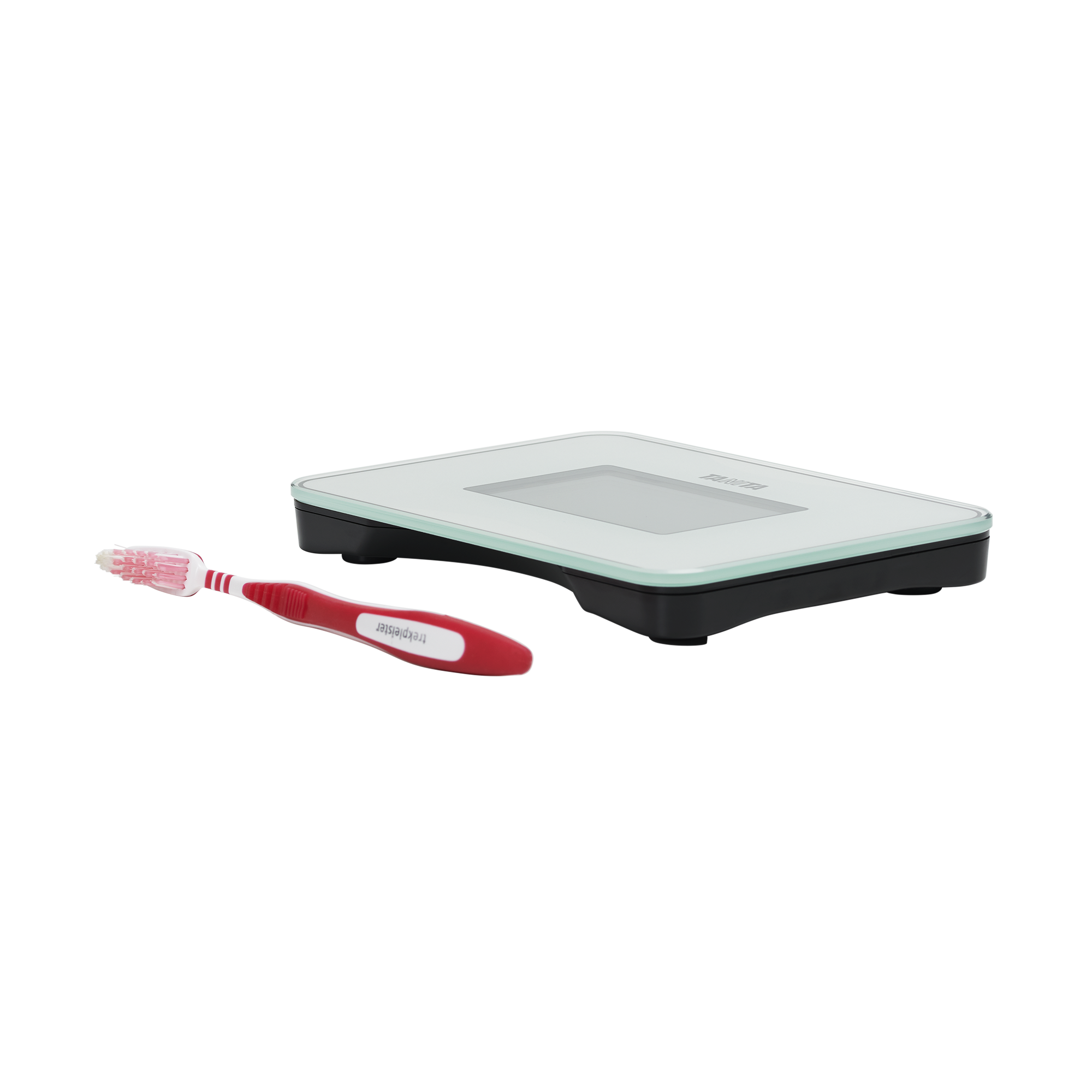Een digitale weegschaal naast een rood-witte tandenborstel op een wit oppervlak. De weegschaal is zwart en zilver.