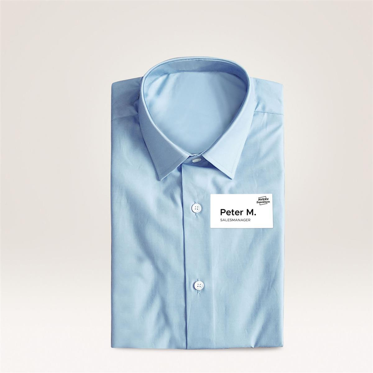 Hellblaues Hemd, gefaltet, mit einem Namensschild, auf dem Peter M., Salesmanager steht.