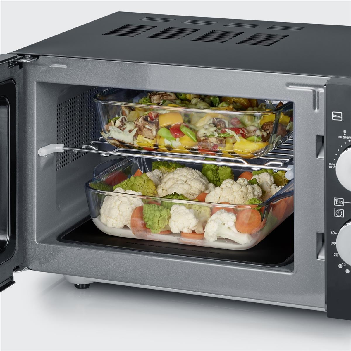 Otwarty piekarnik mikrofalowy z dwoma szklanymi naczyniami z ugotowanym jedzeniem.