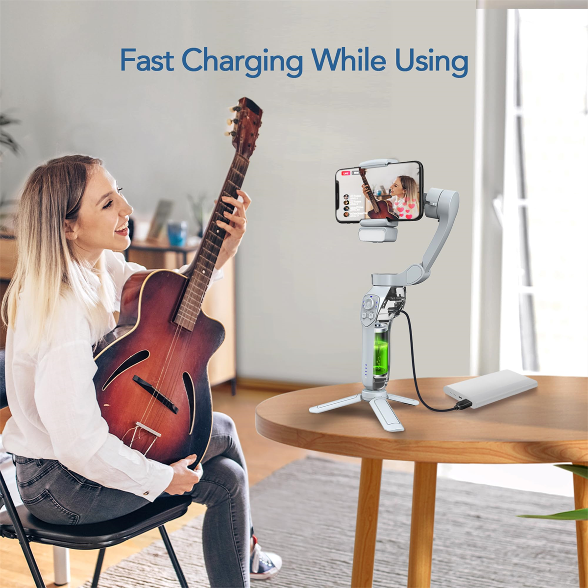 Eine Frau spielt Gitarre, mit einem Telefon auf einem Stativ und einer Powerbank auf einem Tisch.