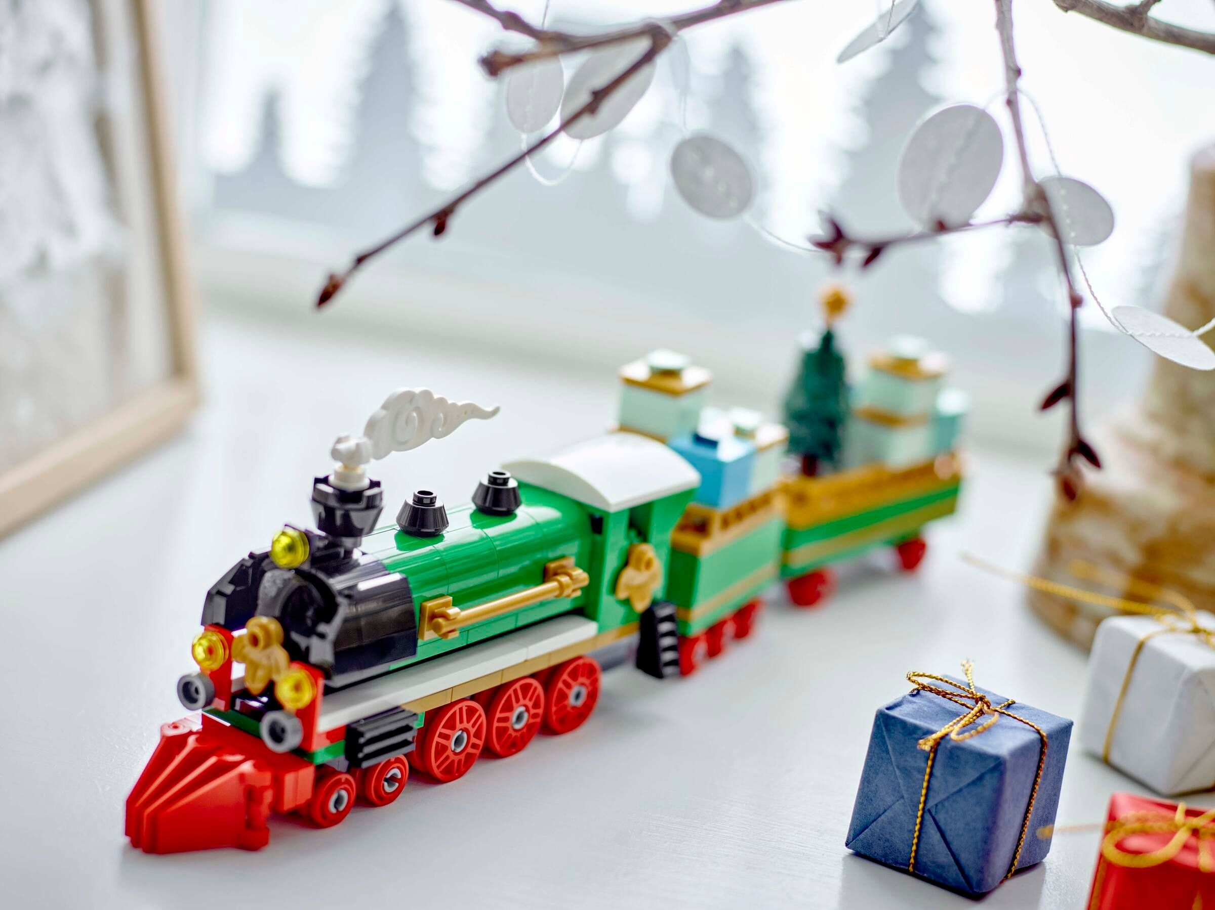 Spielzeugzug, grün und rot, auf weißer Oberfläche, mit Geschenken.