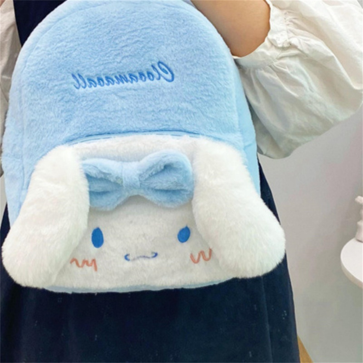 Ein blau-weißer Cinnamoroll-Plüschrucksack mit Schleife und gestickten Details.