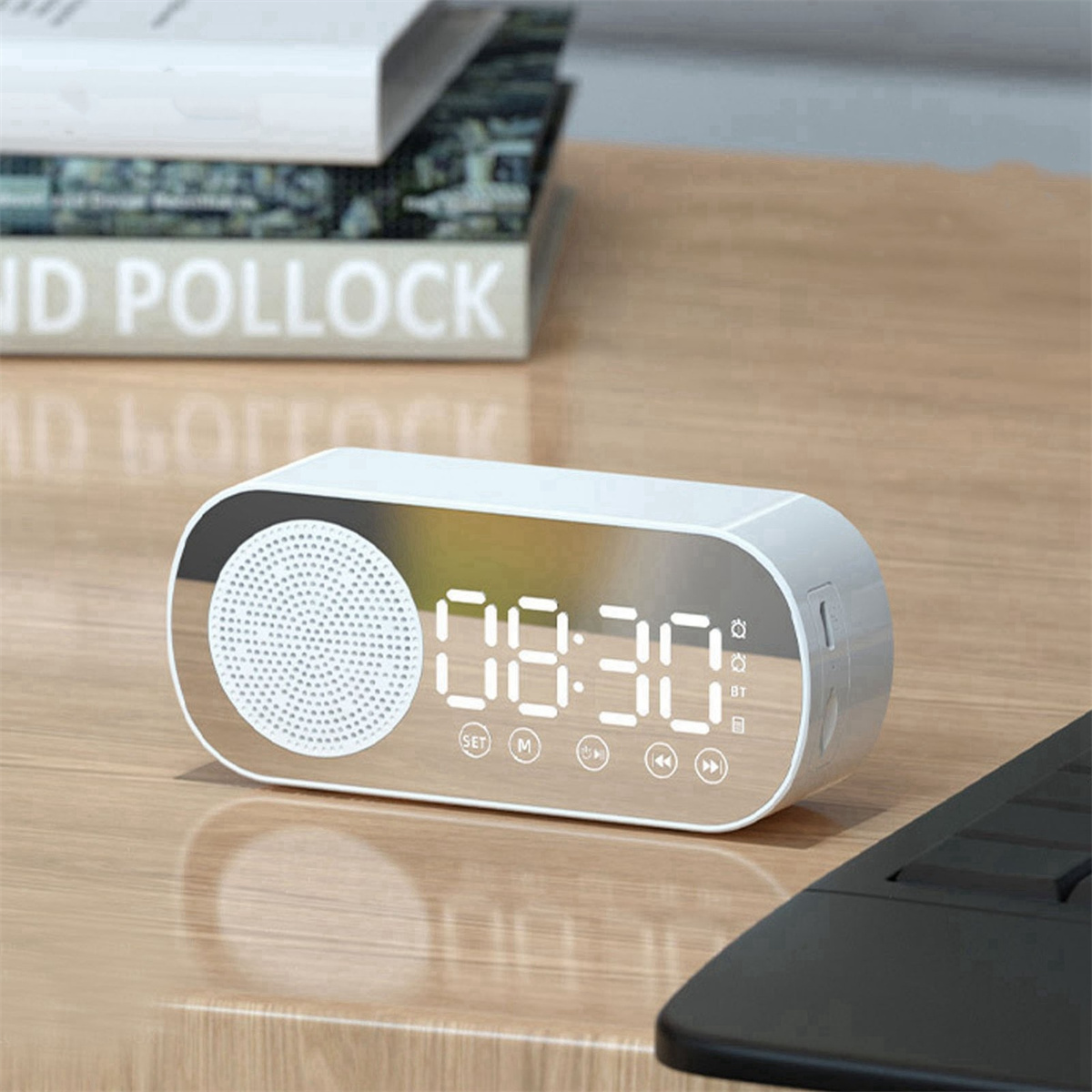 Weiße Digitaluhr mit Lautsprecher, zeigt die Uhrzeit 08:30 an. Bücher im Hintergrund.