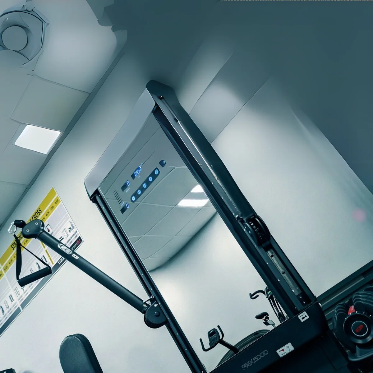 Fitnessapparatuur in een sportschool. Toont een crosstrainer en plafondlampen.