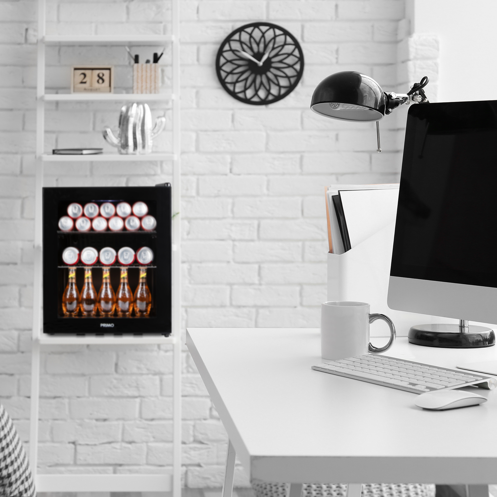Een wit bureau met een minikoelkast, een monitor en een bureaulamp.