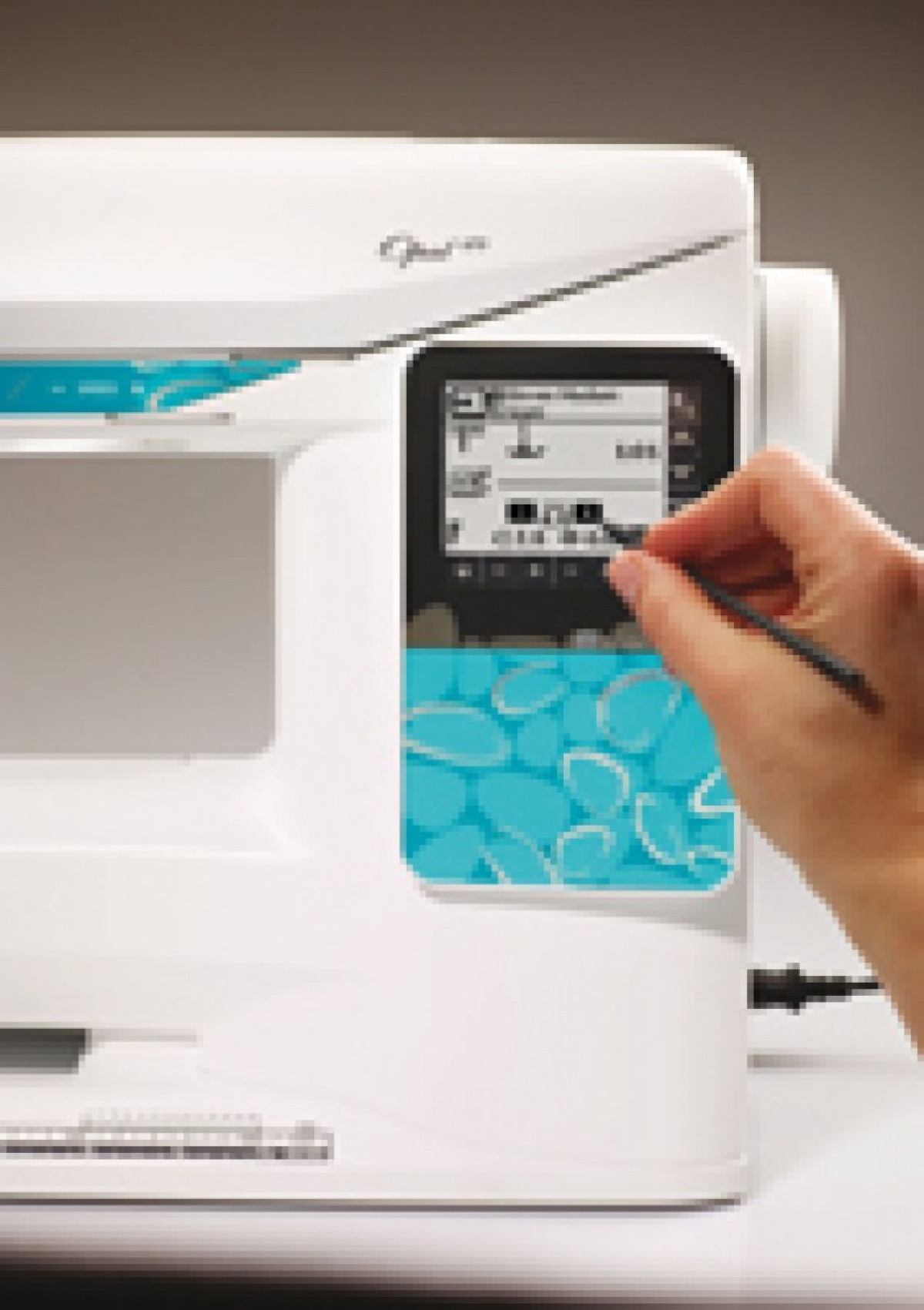 Una mano usa un lápiz óptico en la pantalla táctil de una máquina de coser.