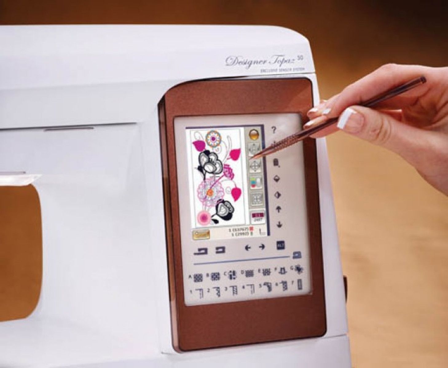 Máquina de coser con pantalla que muestra un diseño de bordado floral. Fondo blanco.