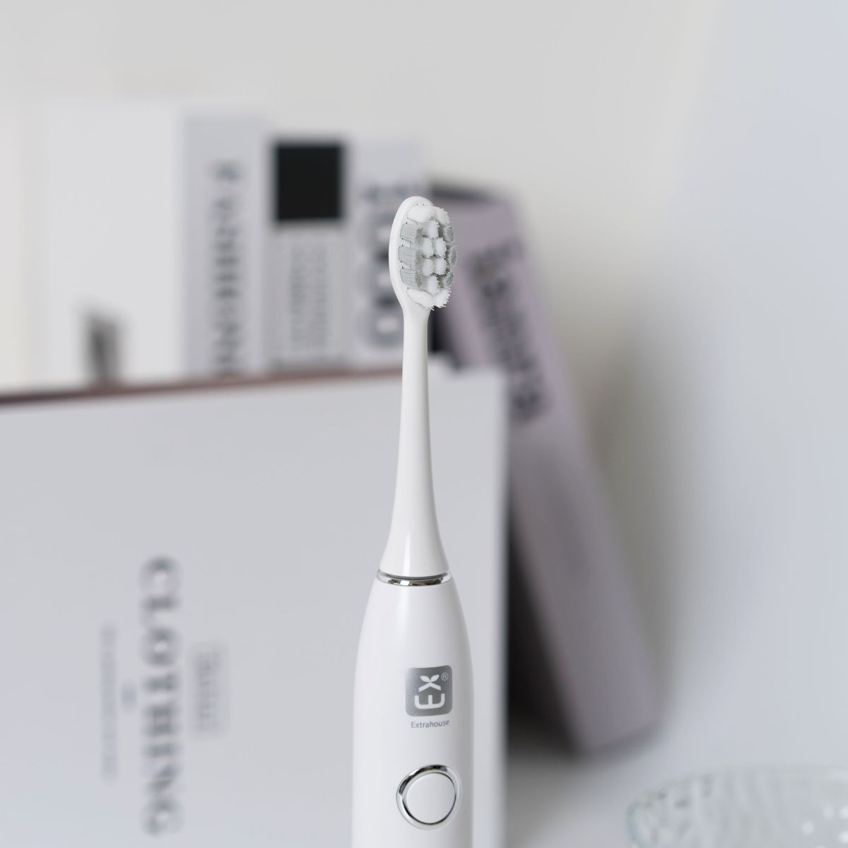Cepillo de dientes eléctrico blanco con libros al fondo.