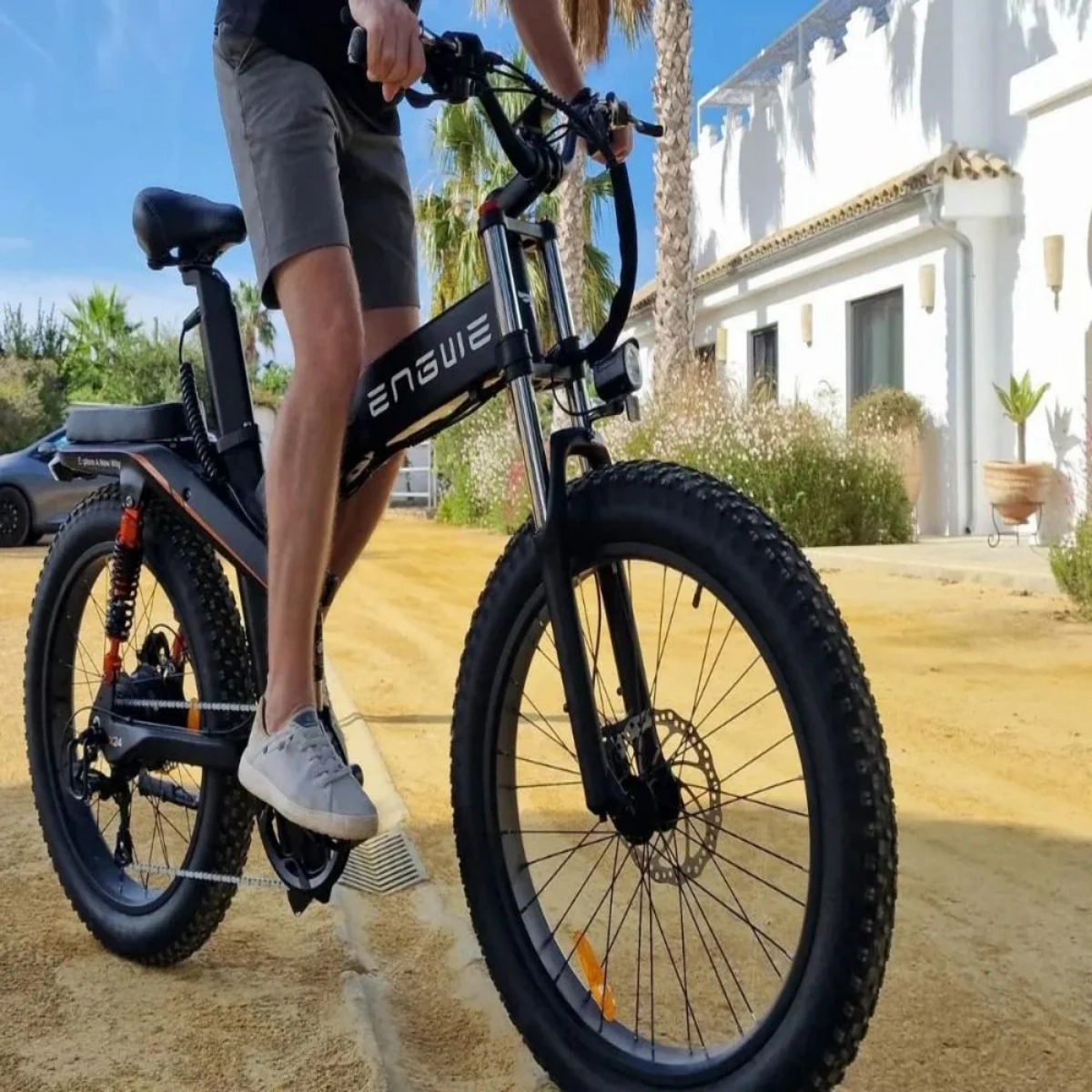 Uomo in sella a una e-bike su uno sterrato, con pneumatici larghi e faro.
