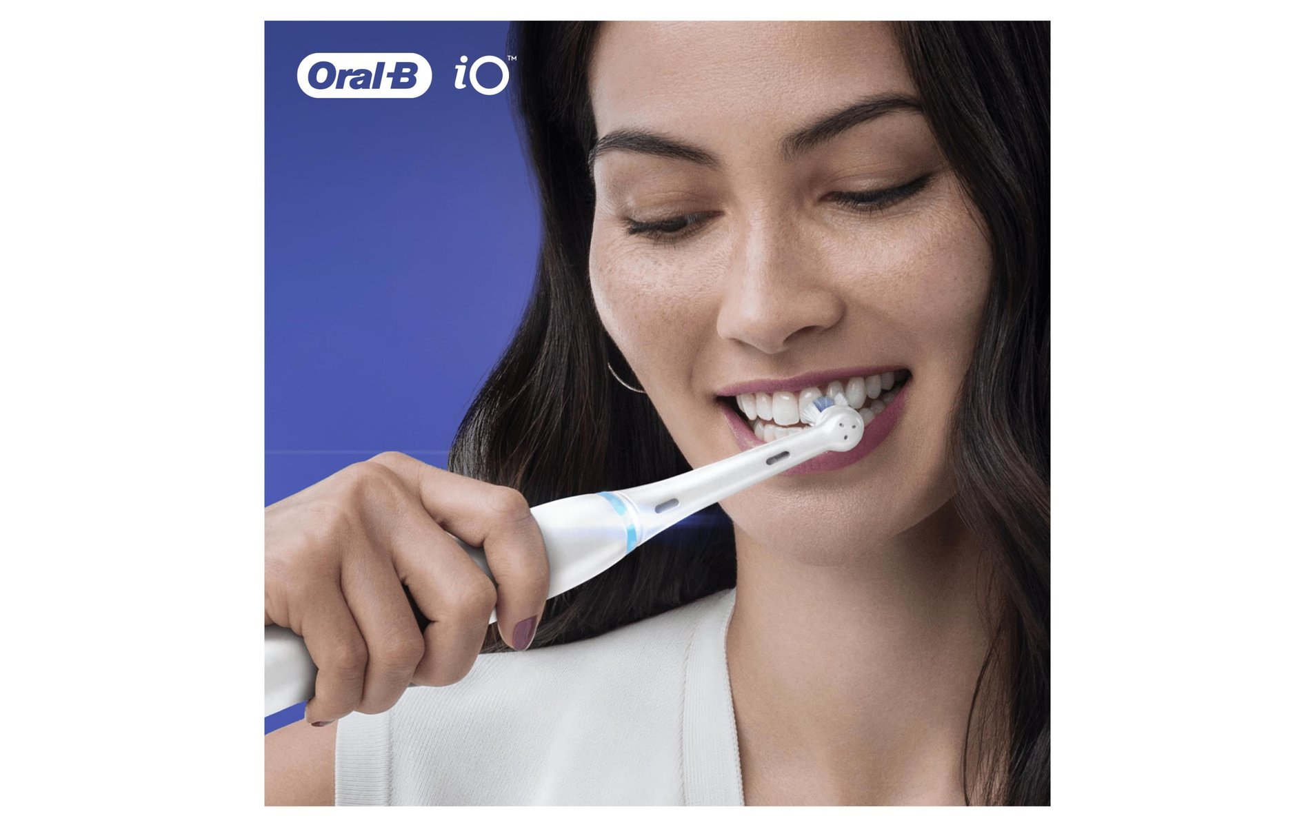 Mujer cepillándose los dientes con cepillo Oral-B iO, primer plano, fondo azul.