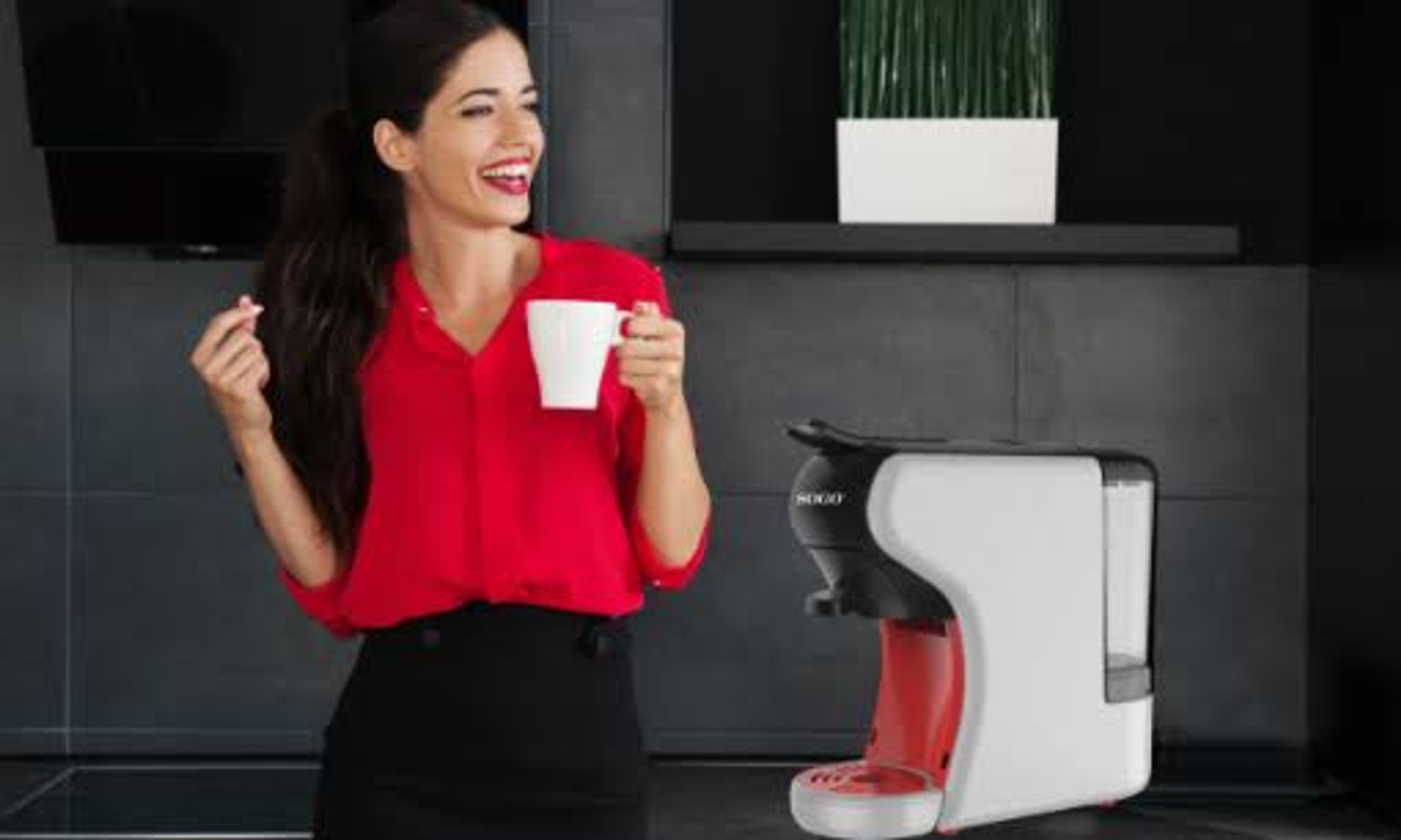 Kobieta w czerwonej koszuli trzymająca biały kubek, uśmiechnięta obok ekspresu do kawy.