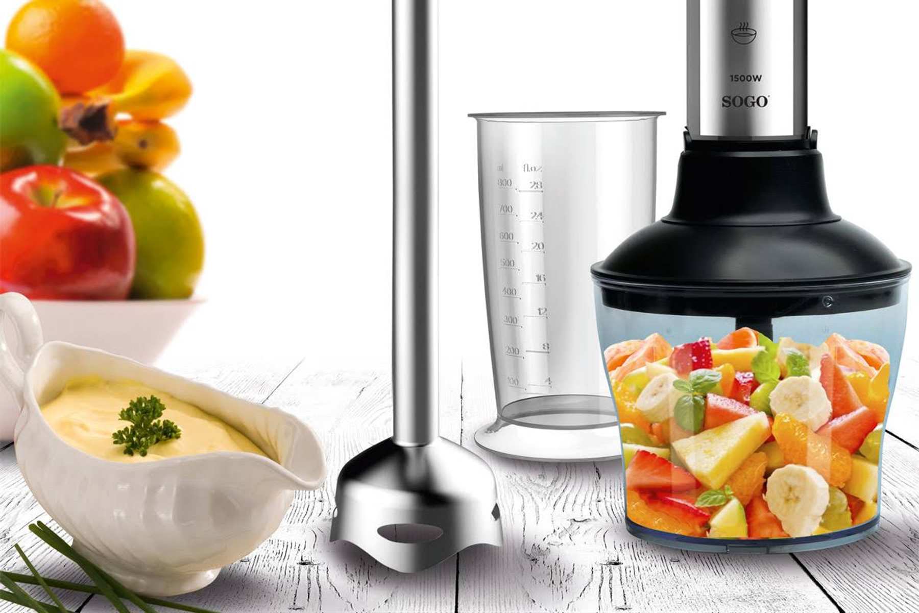 Mixer mit Obstsalat, einem Edelstahl-Mixstab und einem Messbecher mit weißer Soße.