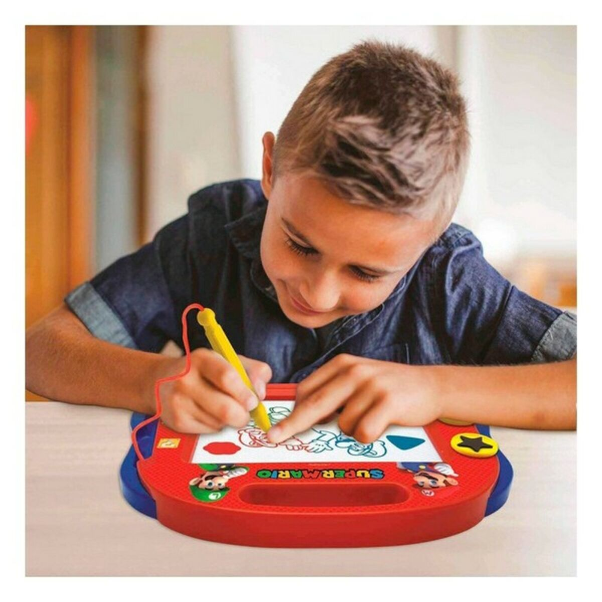 Niño dibujando en un juguete rojo con un bolígrafo amarillo.