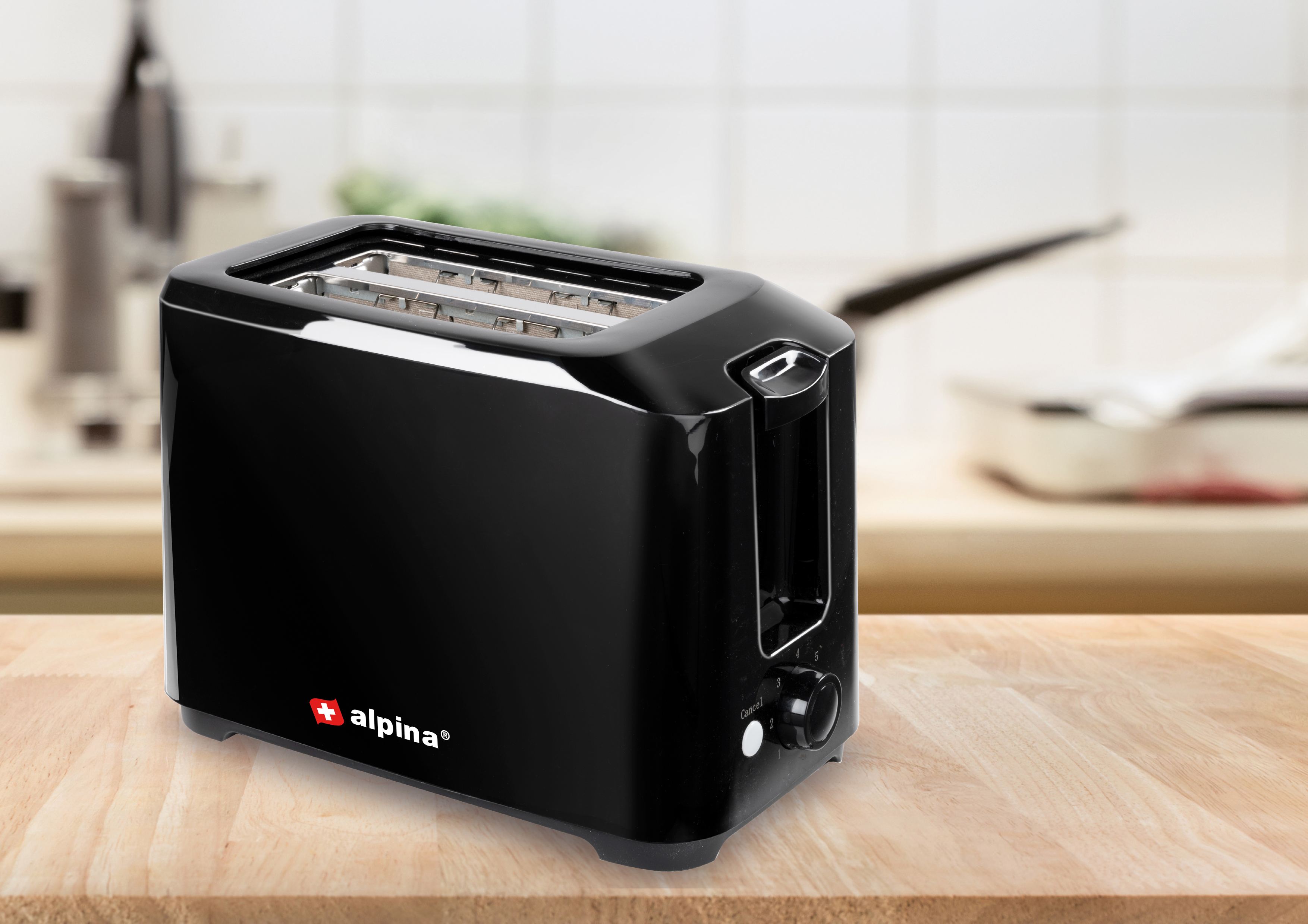 Black toaster on a wooden table with a blurry kitchen background.