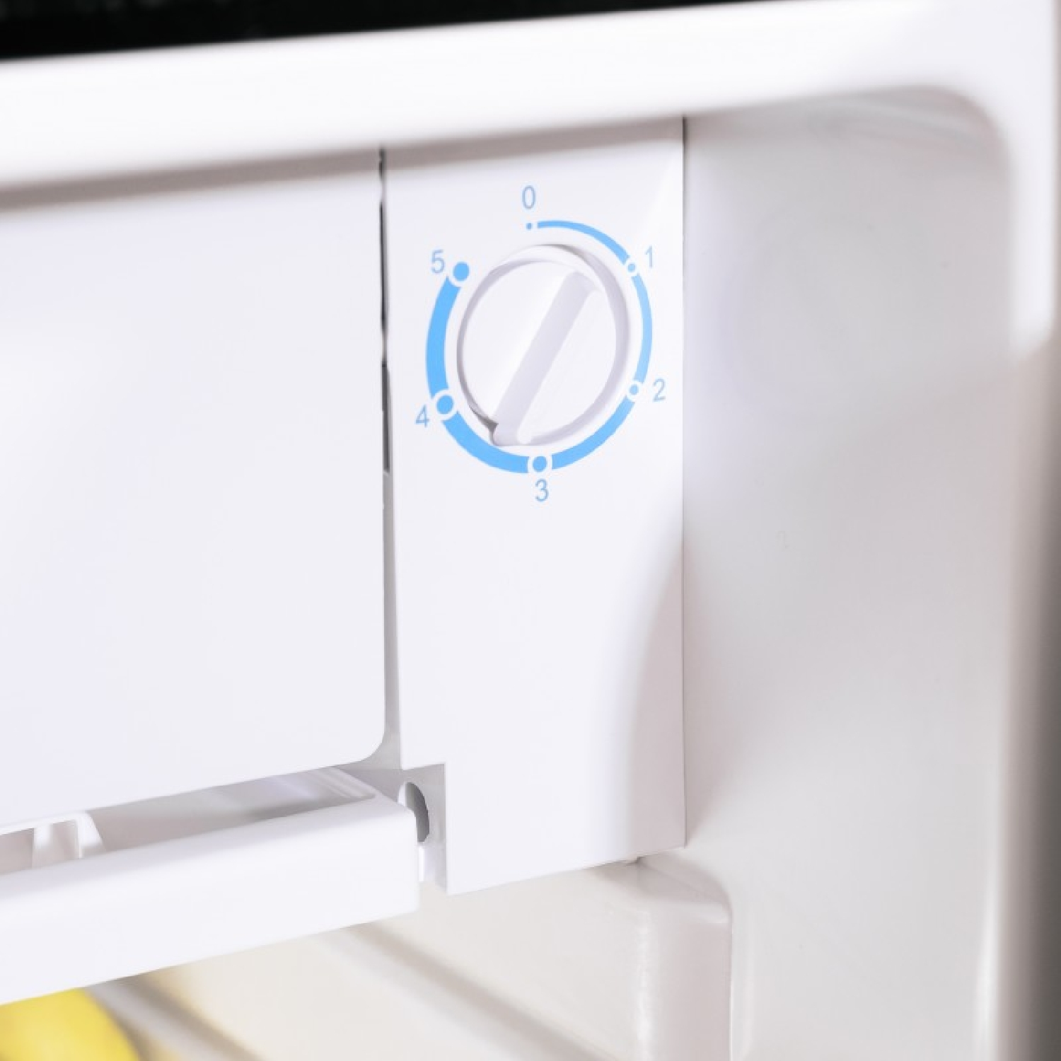 Primo piano del pannello di controllo di un frigorifero bianco. Ha un quadrante da 0 a 5 in numeri blu.