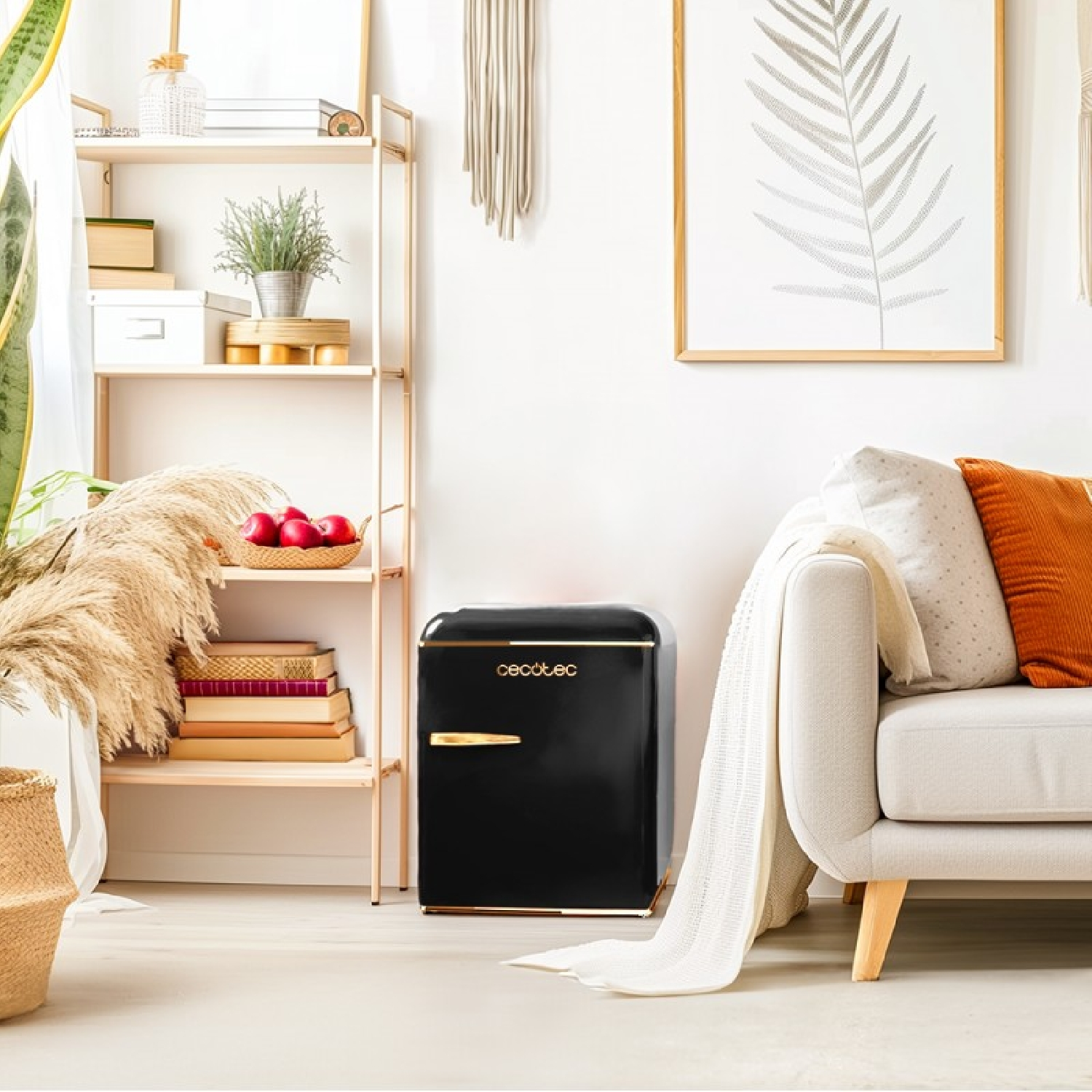 Czarna mini lodówka retro ze złotymi akcentami, obok półki i sofy.