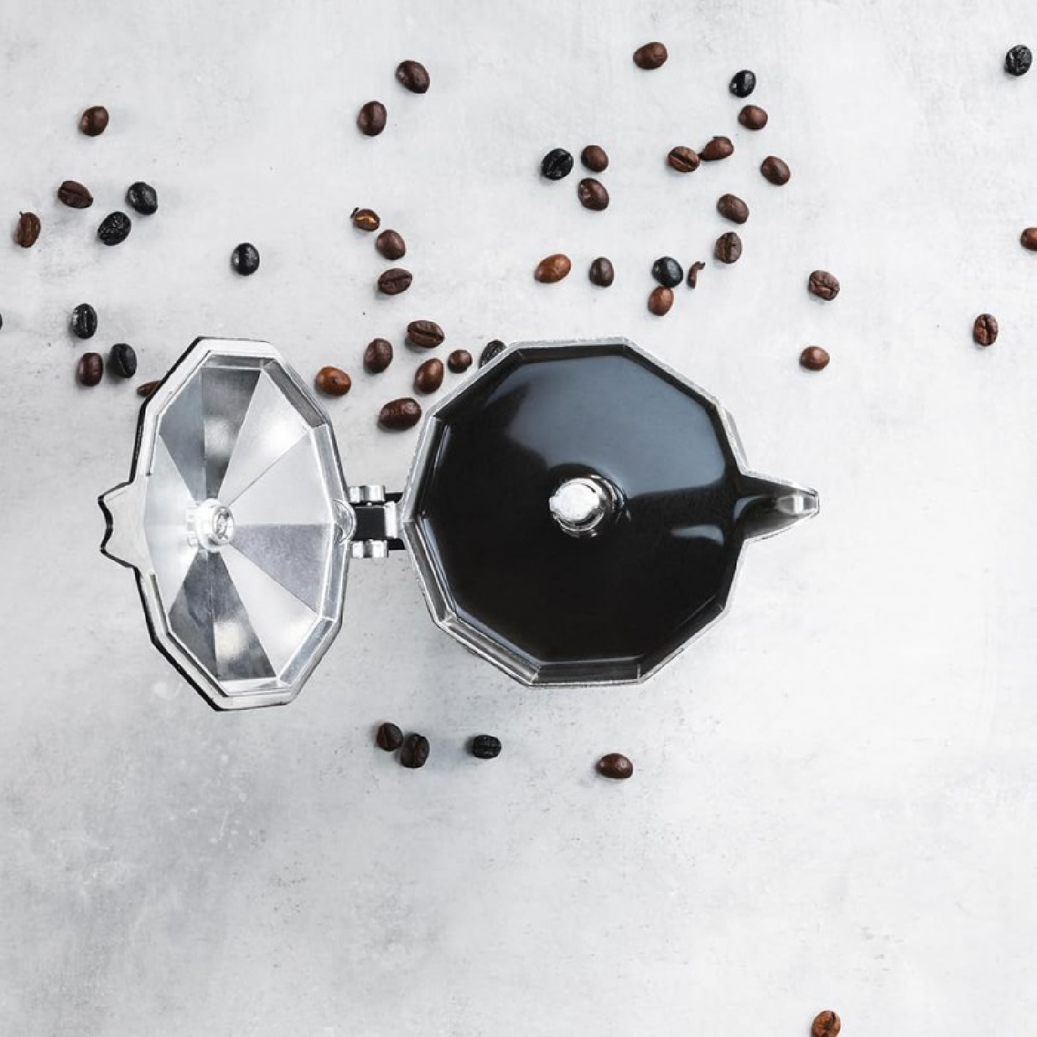 Draufsicht auf eine offene Mokkakanne mit Kaffee. Kaffeebohnen verstreut.