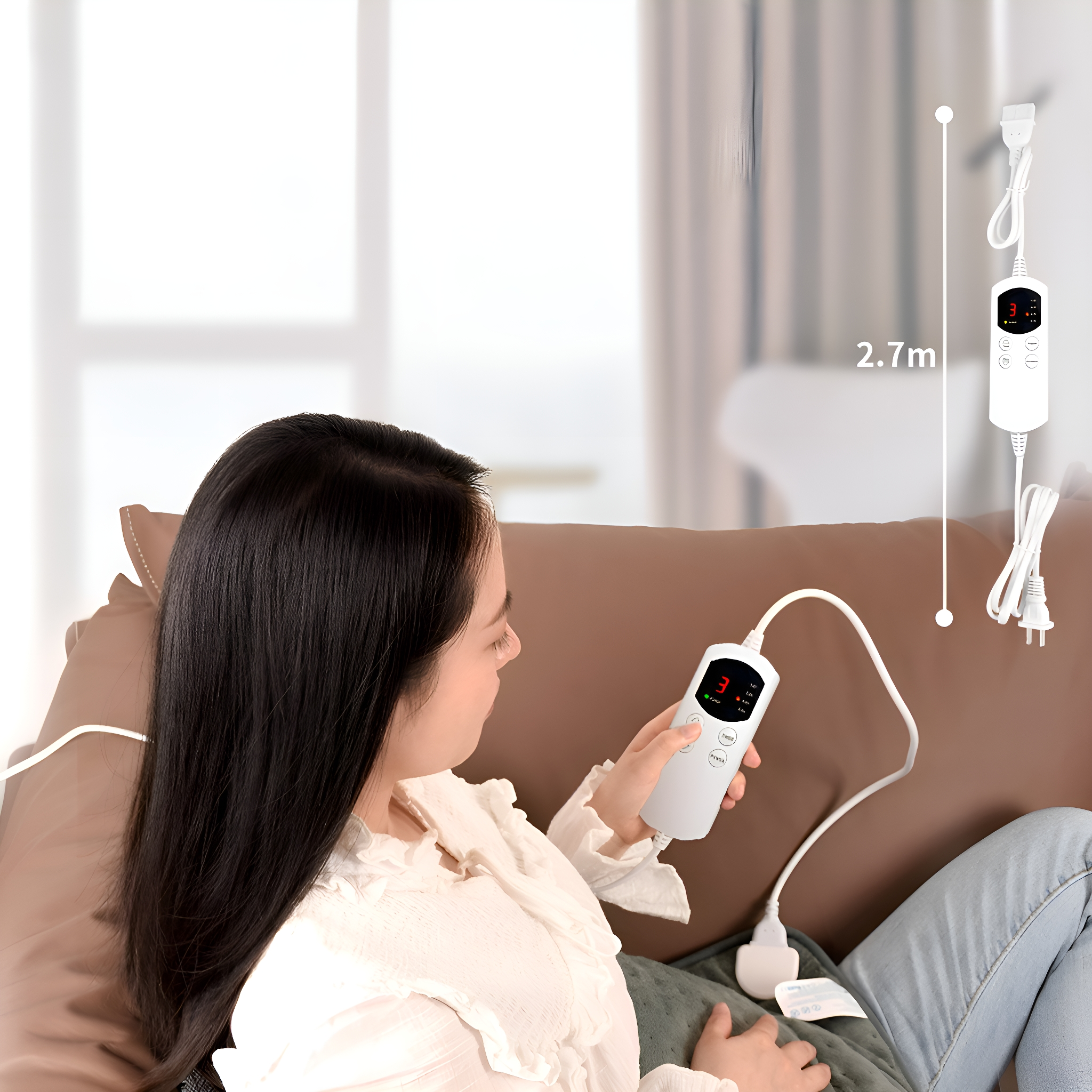 Frau benutzt eine Heizkissen-Steuerung auf einem Sofa. 2,7m Kabel sichtbar. Braunes Sofa.