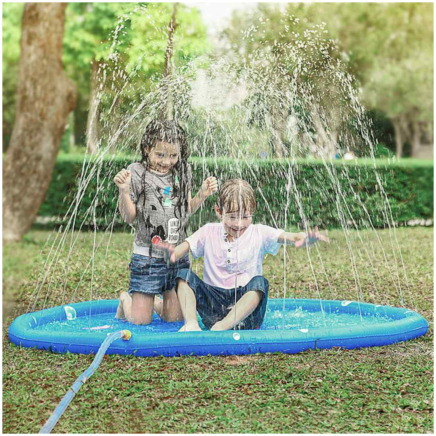 Due bambini che giocano in una piscina blu con l'acqua che schizza. Erba verde e uno sfondo sfocato di alberi.