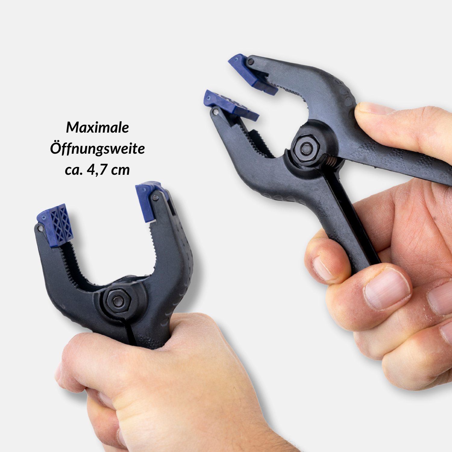Zwei schwarze Klemmen mit blauen Spitzen. Eine in der Hand, andere auf Weiß.