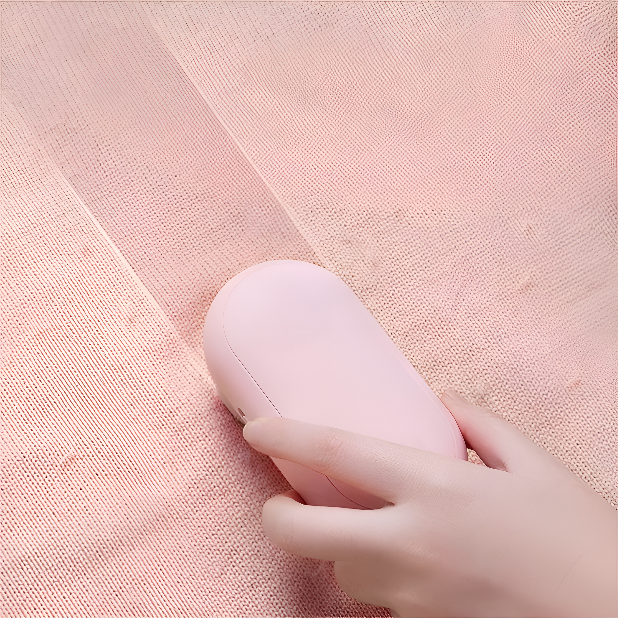 Eine Hand benutzt einen rosa Fusselentferner auf rosa Stoff.