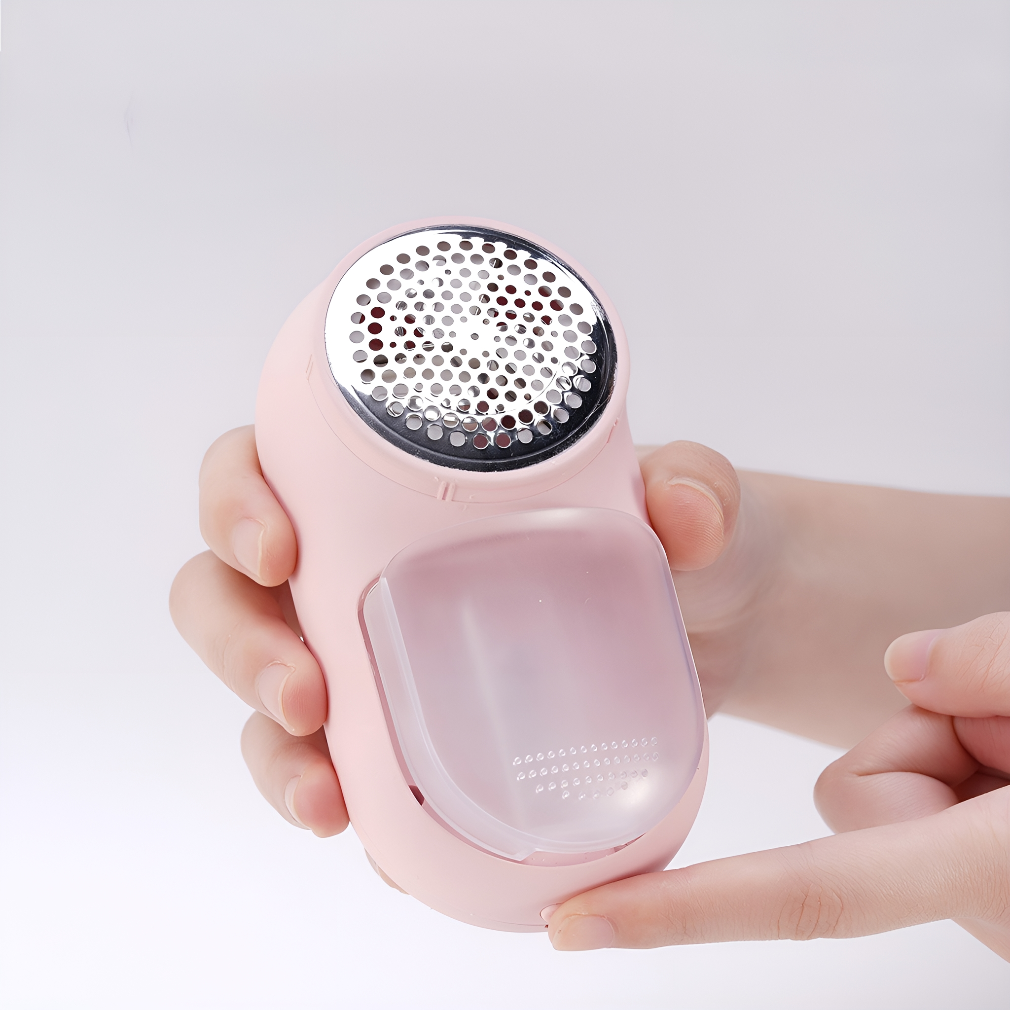 Eine Hand, die ein rosa, tragbares Fusselentfernergerät hält.