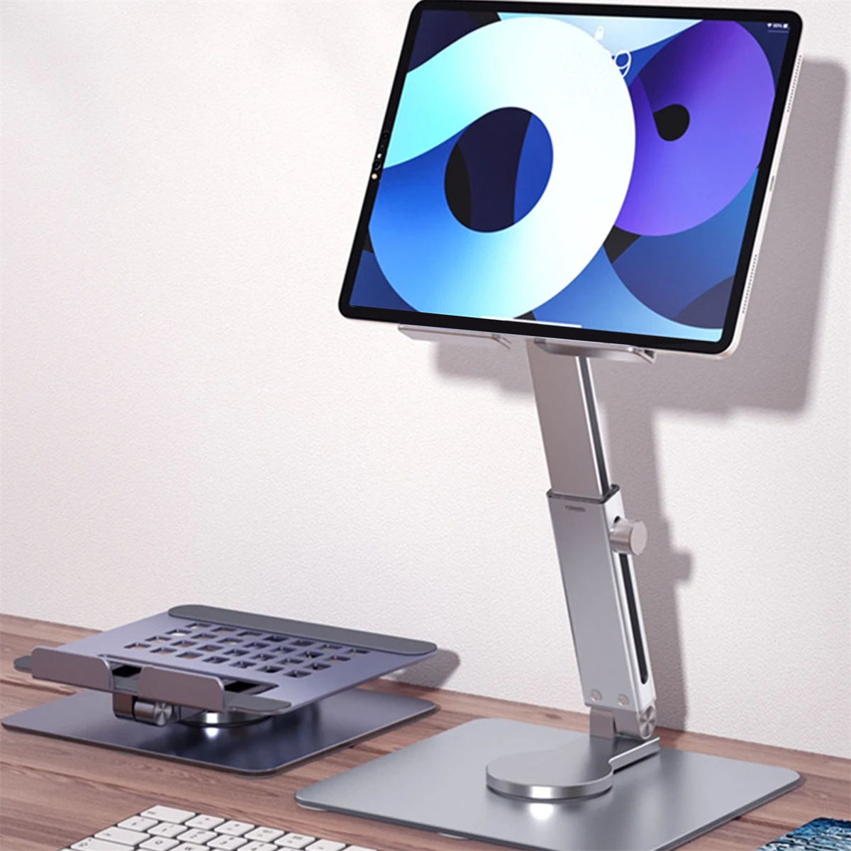 Silberner Tablet-Ständer mit Tablet, Tastatur und weißem Wandhintergrund.