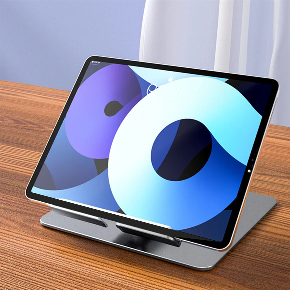 Tablet auf einem Ständer. Das Tablet zeigt ein buntes, abstraktes Bild. Der Ständer steht auf einem Holztisch.