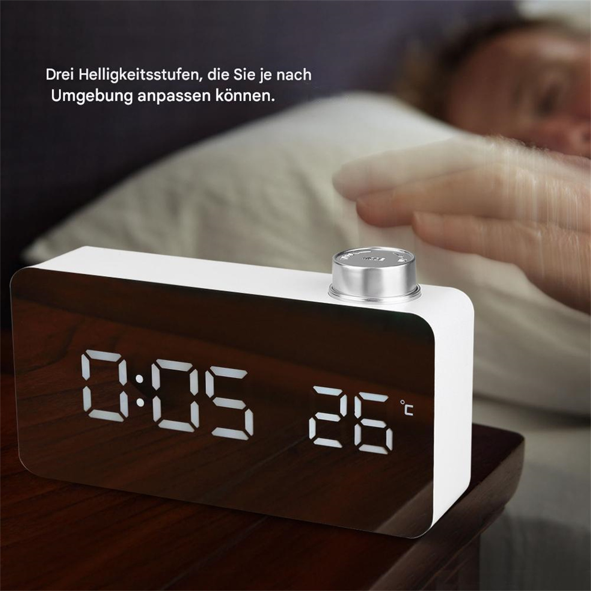 Ein weißer digitaler Wecker, der die Uhrzeit anzeigt. Eine Hand greift nach dem Wecker.