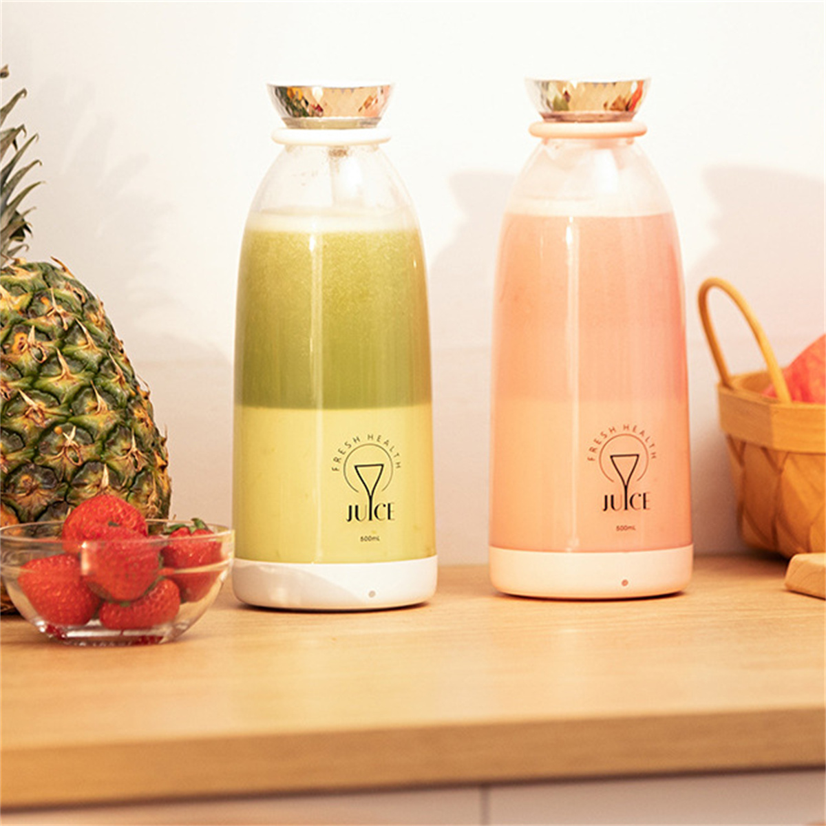 Zwei Mixer mit grünem und rosa Saft, mit Erdbeeren und einer Ananas.