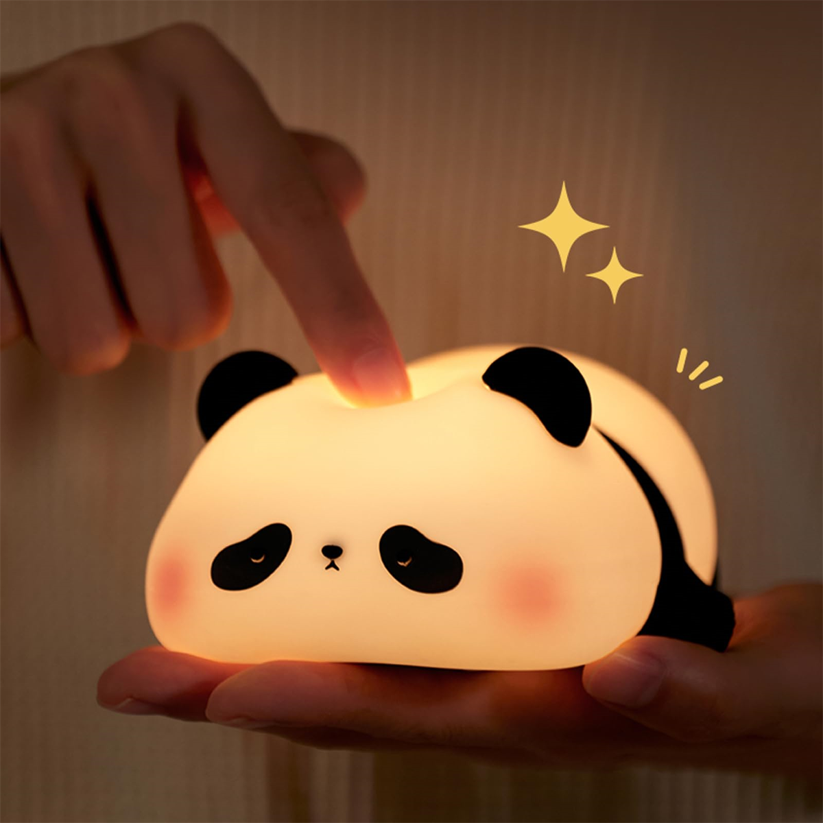 Ein panda-förmiges Nachtlicht mit schwarz-weißen Details. Ein Finger berührt die Oberseite.