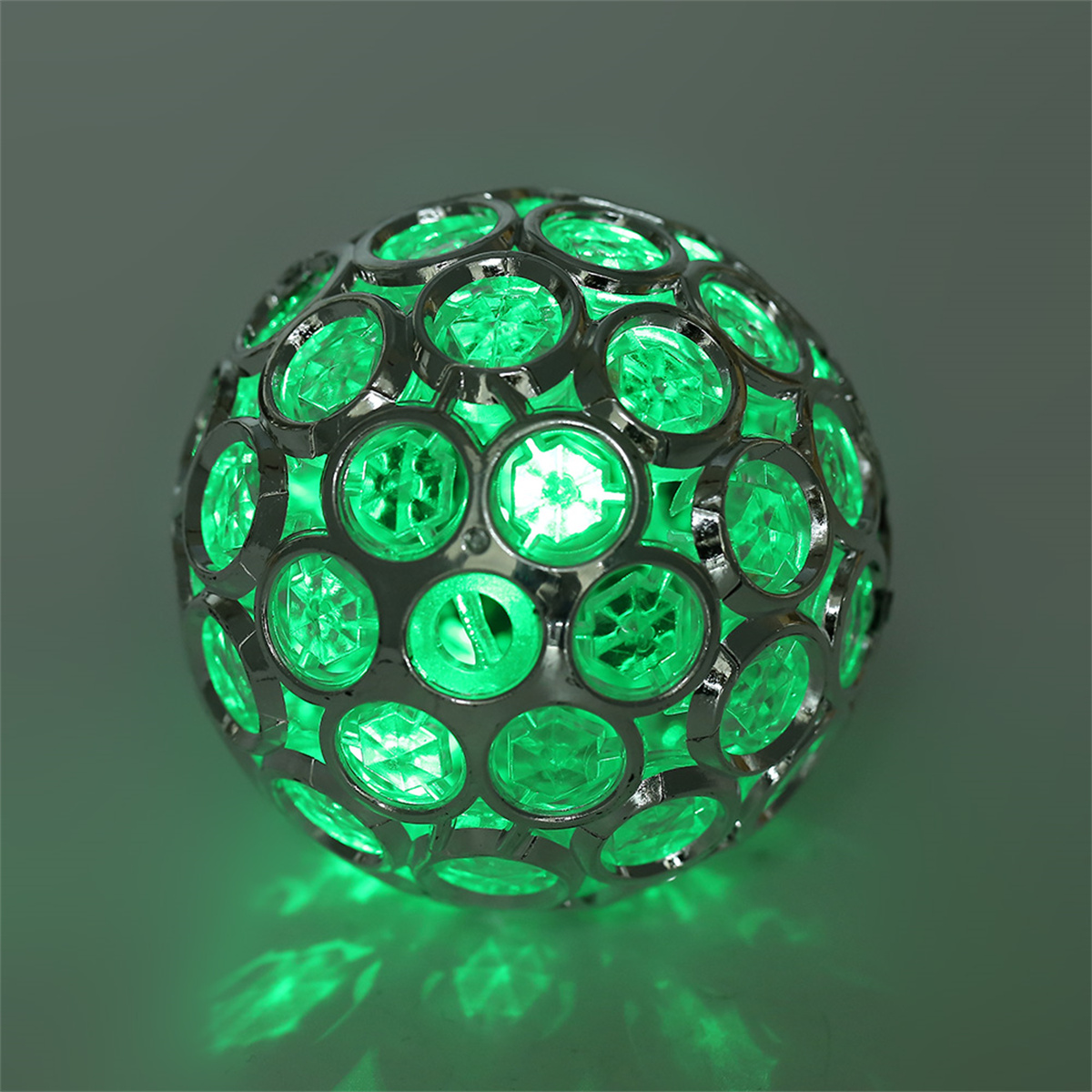 Grün leuchtende dekorative Kugel. Die Kugel ist metallisch und hat viele grüne Lichter im Inneren.