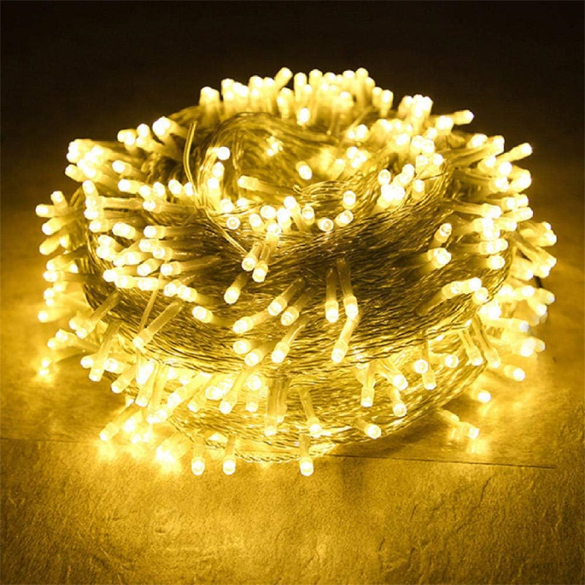 Ein Ball aus warmweißen LED-Lichterketten. Die Lichter sind in einem dichten Bündel angeordnet und leuchten hell auf braunem Untergrund.
