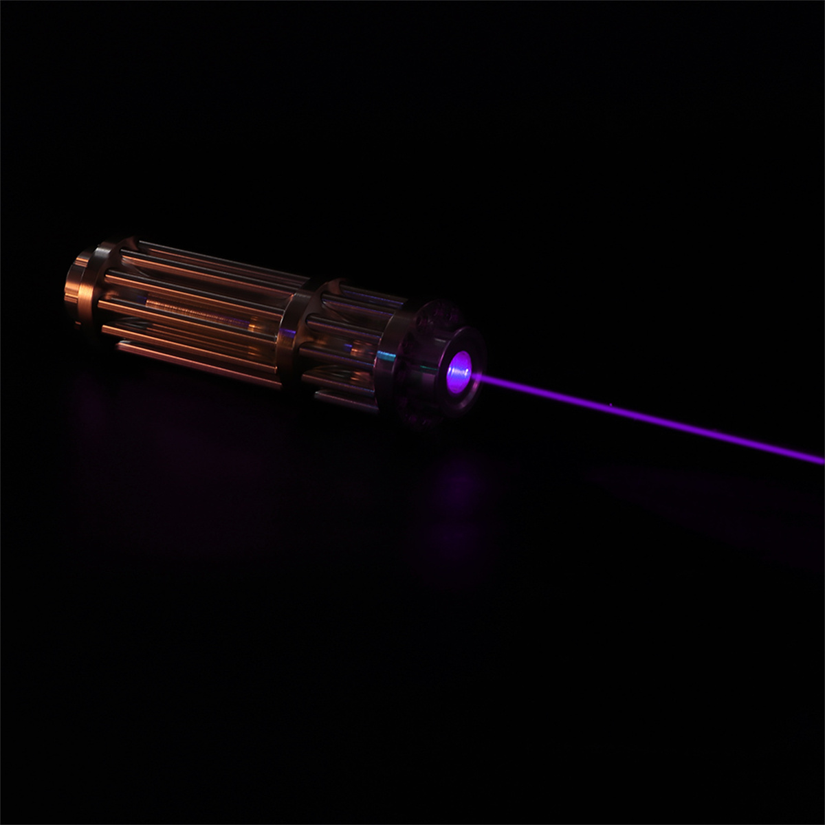 Ein violetter Laserpointer sendet einen Strahl aus. Er befindet sich auf dunklem Hintergrund.