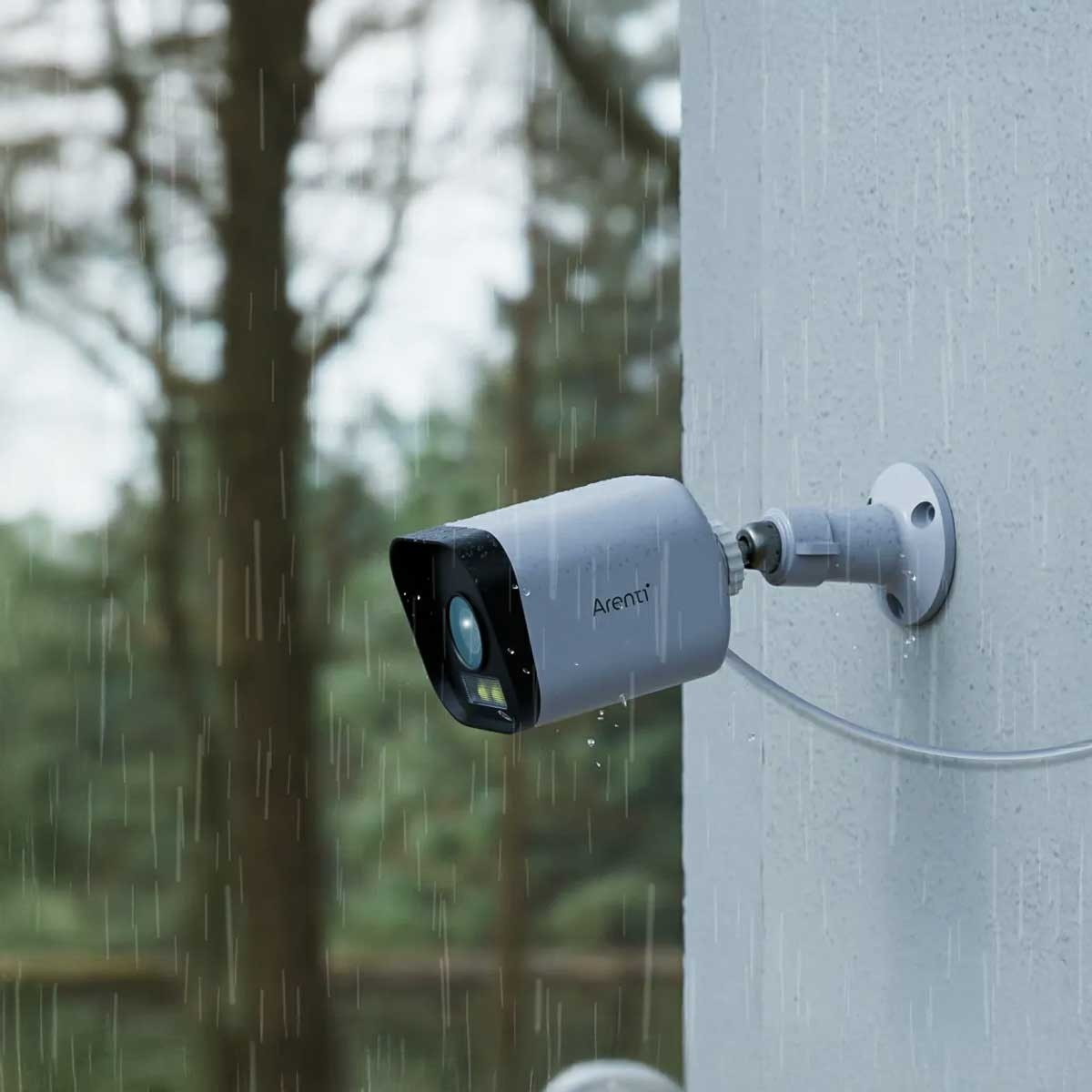 Eine graue Überwachungskamera, die an einer Wand befestigt ist, mit Regen. Die Kamera ist nach links abgewinkelt.