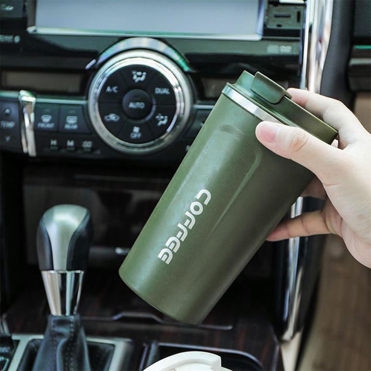 Ein grüner Kaffeebecher in einem Auto. Das Wort "COFFEE" ist aufgedruckt.