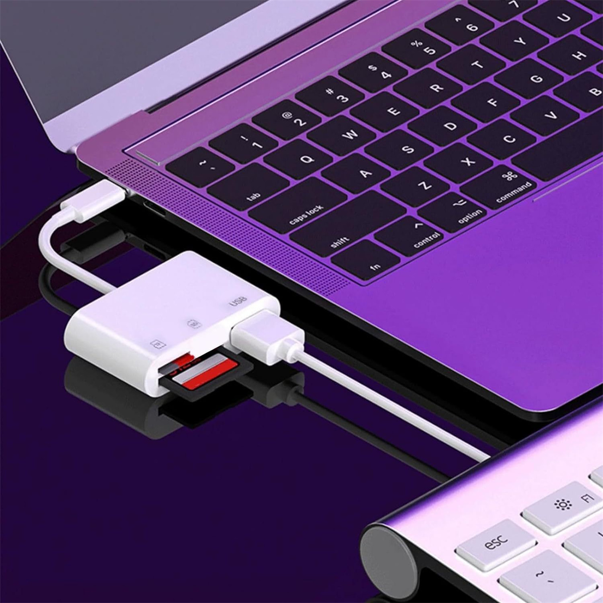 Ein weißer Adapter, der mit einem lila Laptop verbunden ist. Eine rote SD-Karte ist eingesetzt.