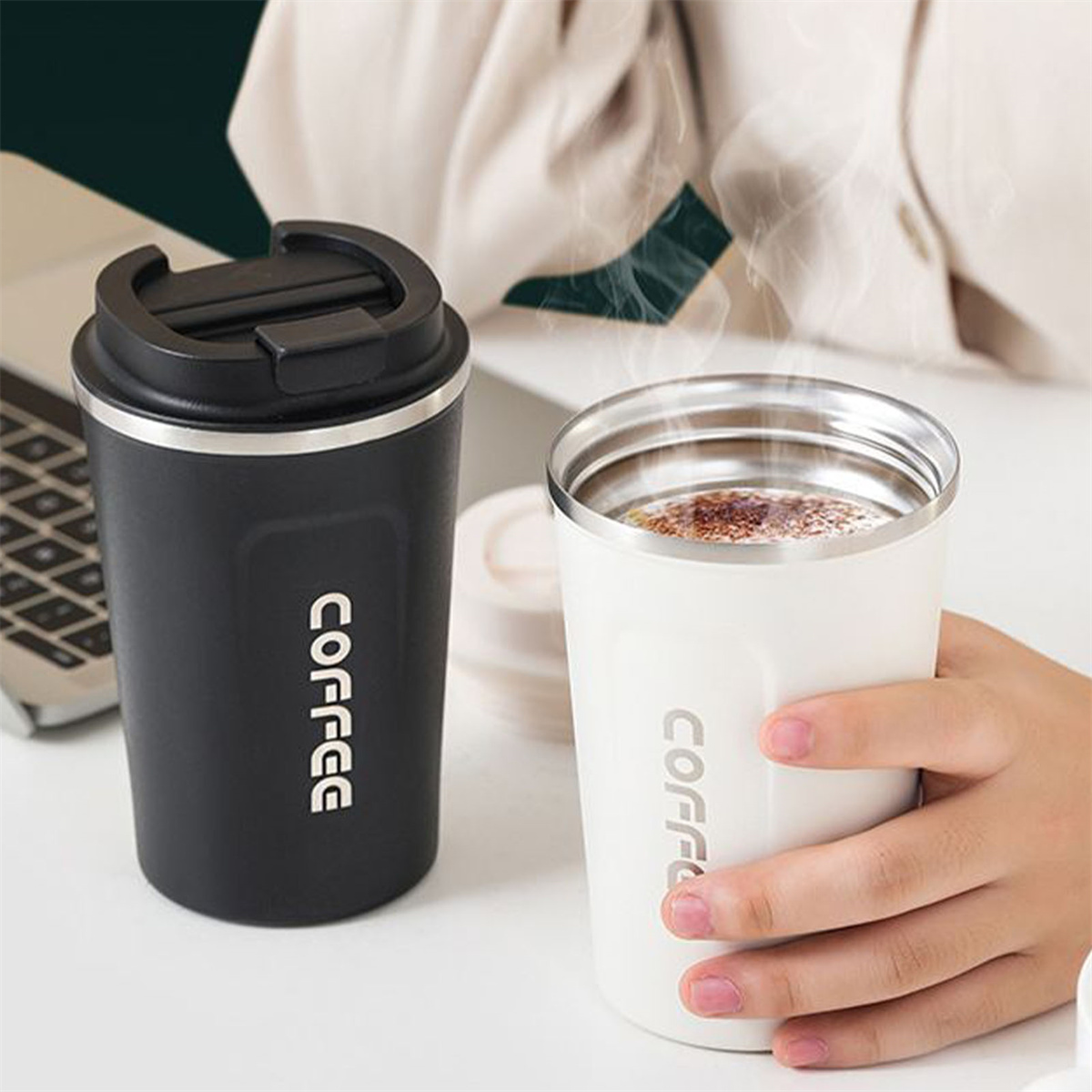 Zwei Kaffeebecher, einer schwarz, einer weiß. Beide haben 'COFFEE' aufgedruckt. Hand hält weiße Tasse.