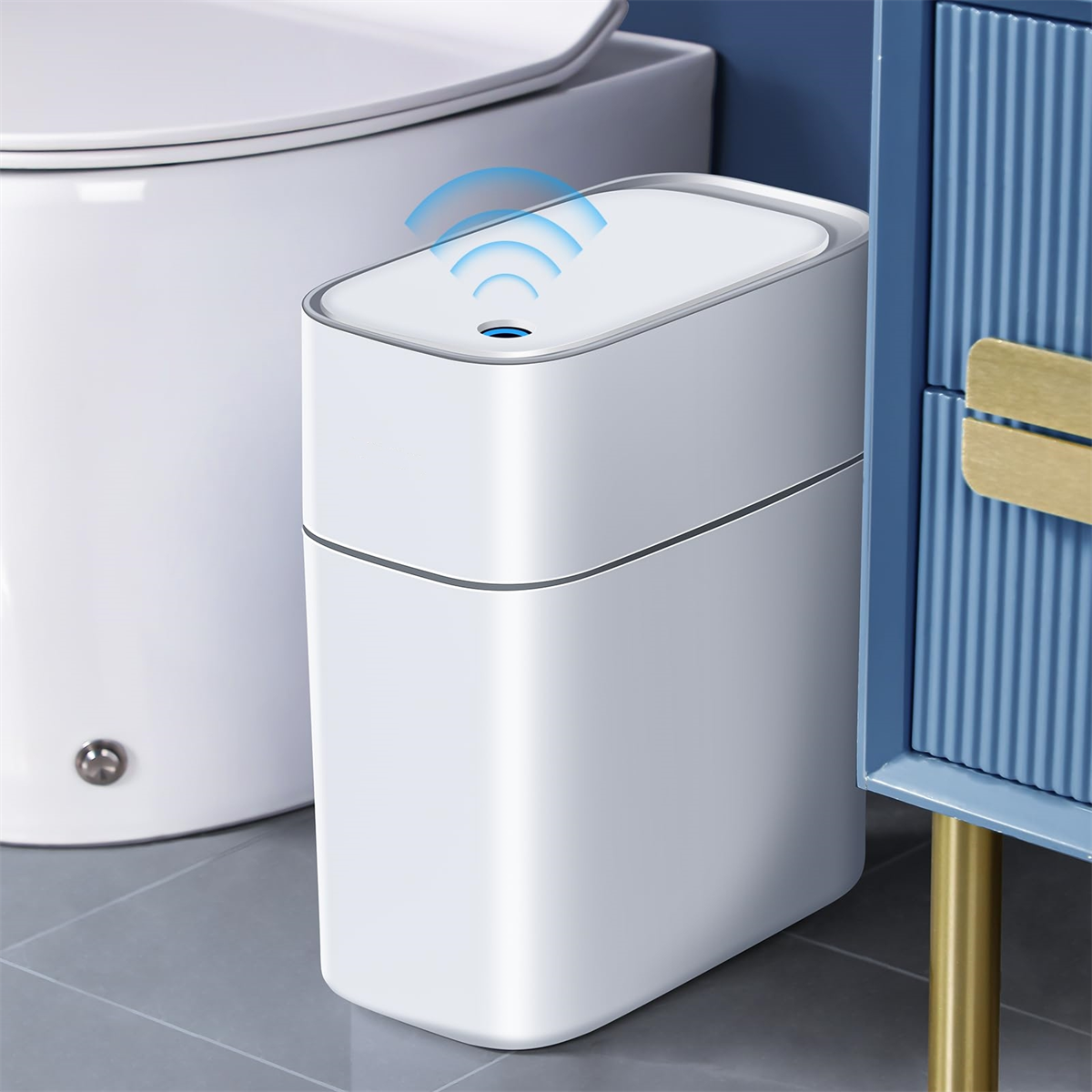 Weißer intelligenter Mülleimer mit blau akzentuiertem Deckel, in der Nähe von Toilette und Schrank.