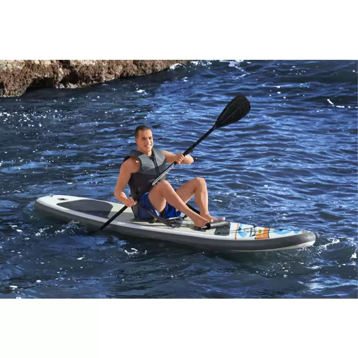 Hombre en una tabla de remo con un remo. Agua, cielo y sol en el fondo.