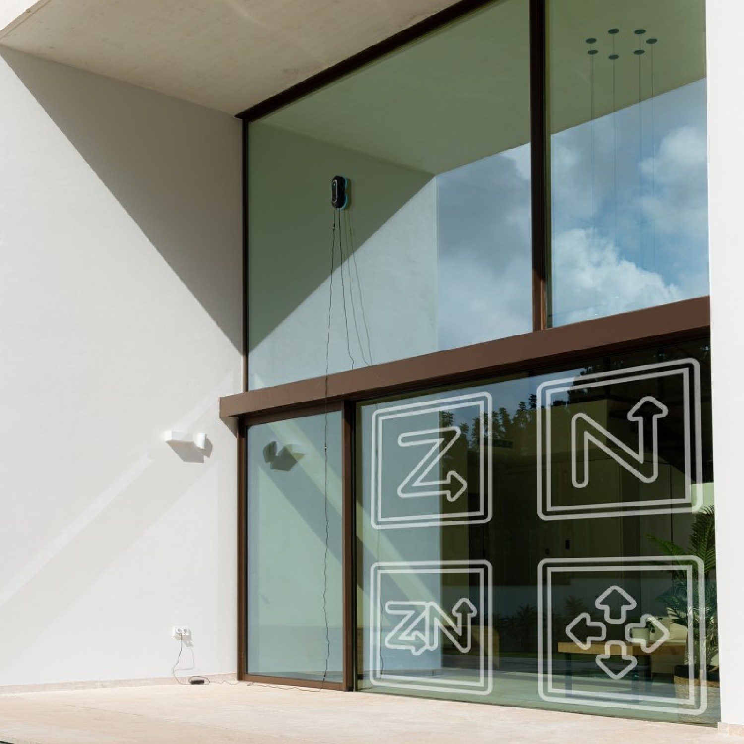 Ein Fenster mit Symbolen, ein Fensterputzer auf dem Glas und eine weiße Außenwand.