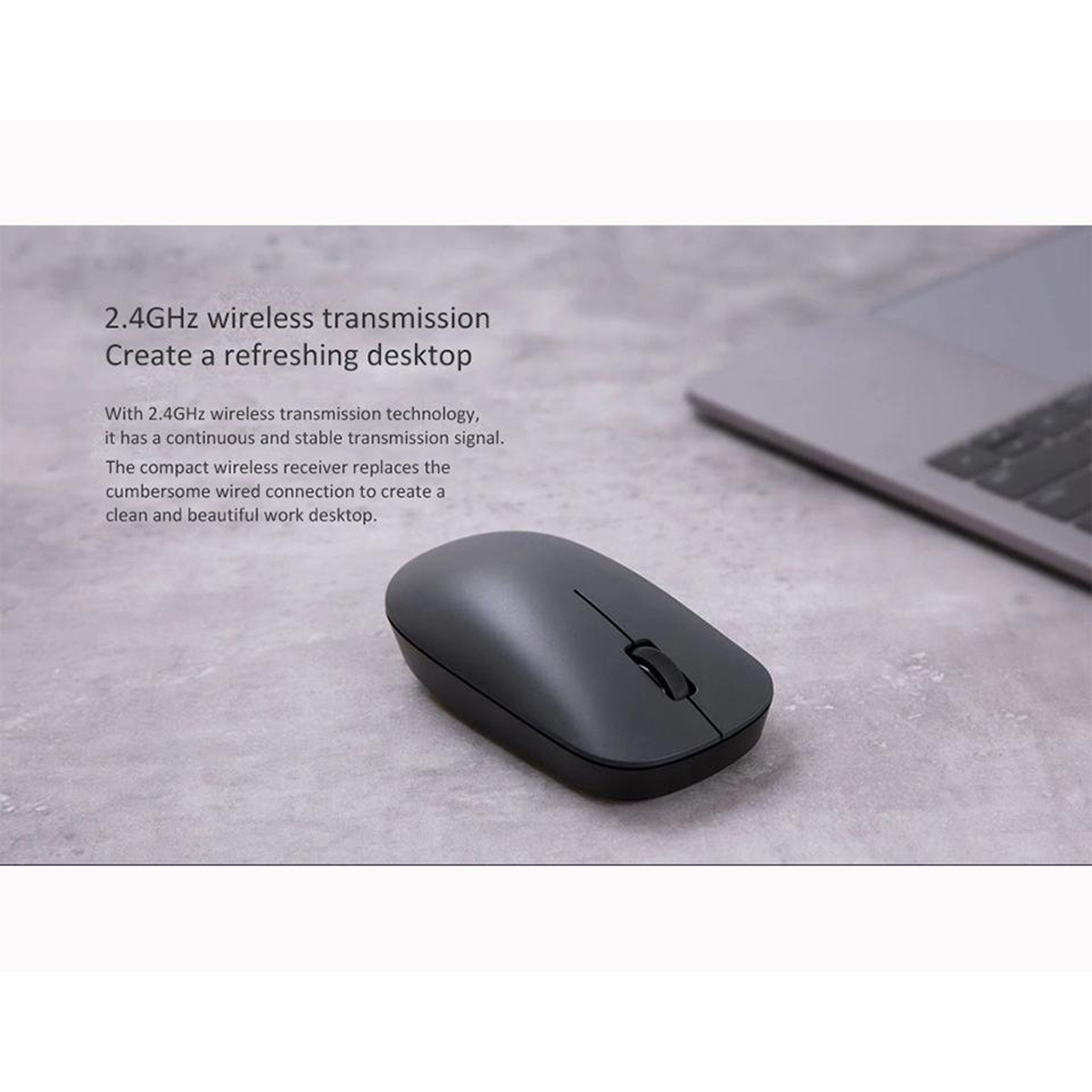 Souris sans fil sur une surface. La souris est grise. Fond : un ordinateur portable et une surface.