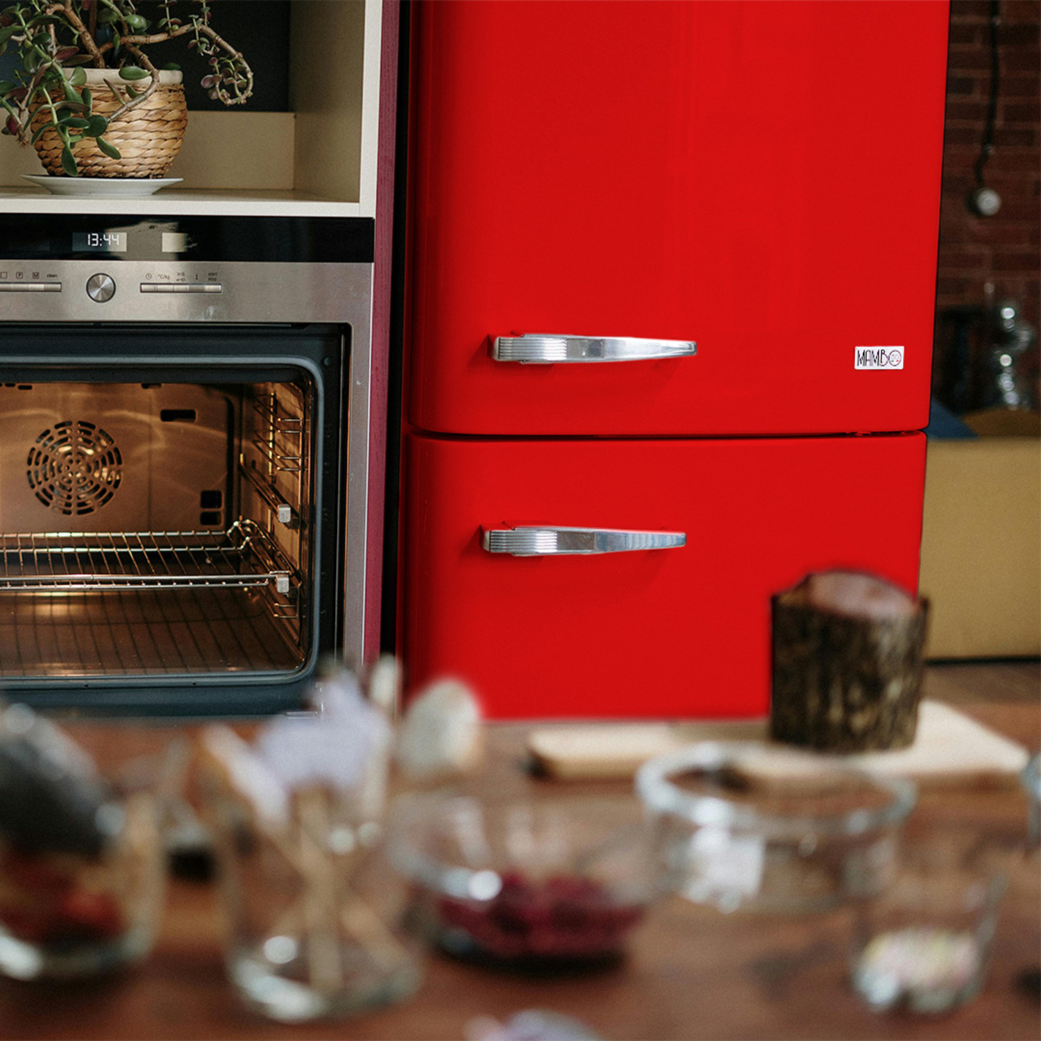 Un frigorifero rosso e un forno argentato con cibo dentro, e un tavolo.