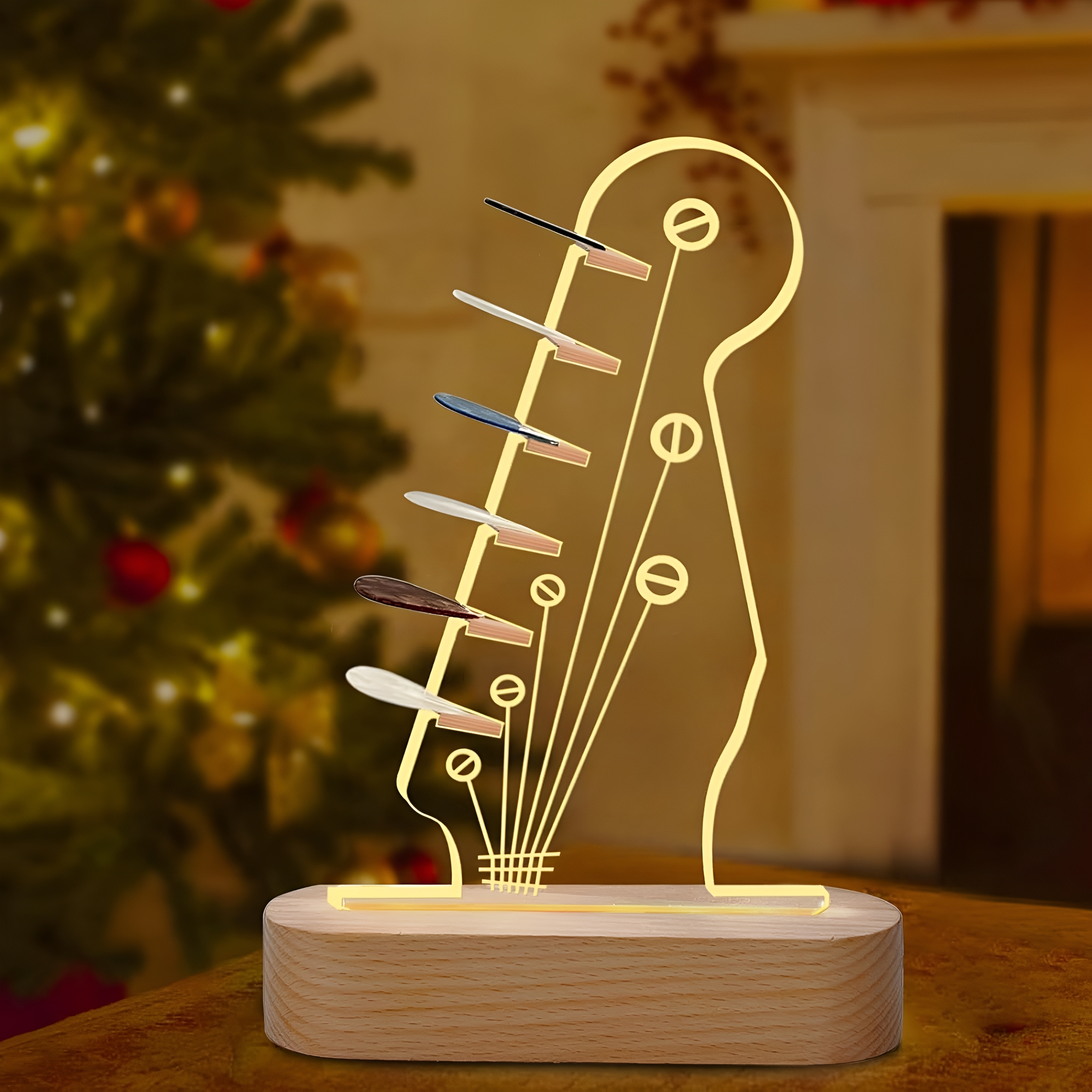 Gitarrenkopf-förmige Lampe. Holzsockel, gelbes Leuchten. Weihnachtsbaum im unscharfen Hintergrund.