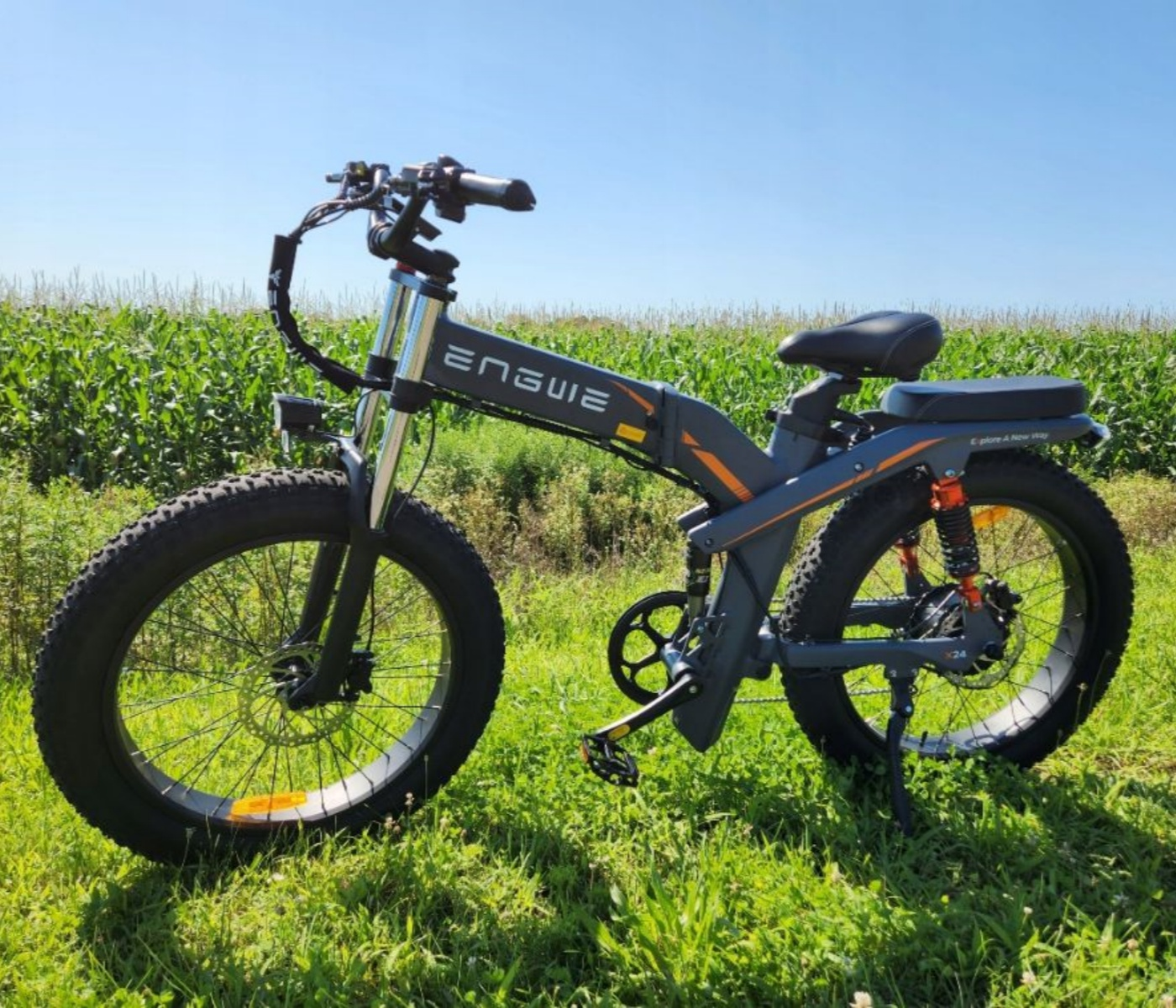 Una bici elettrica sull'erba verde con un campo sullo sfondo e cielo blu.